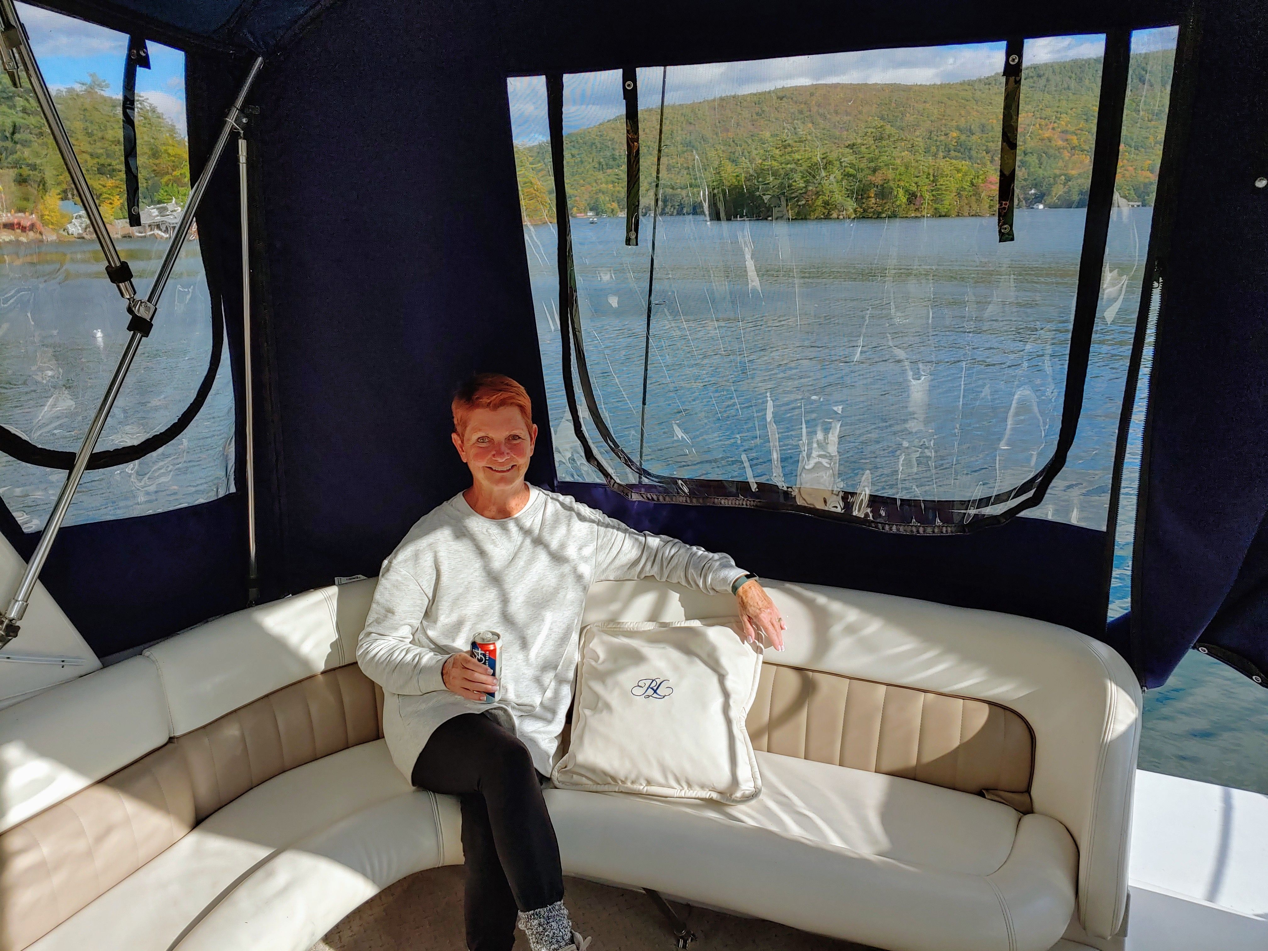 Person sitting on a boat overlooking a lake and wooded hills.