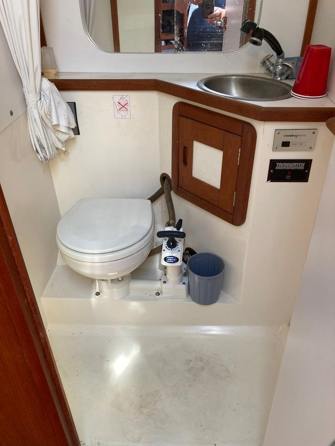 The image shows the bathroom of a 1990 Catalina 42 Tricabin with a toilet and sink.