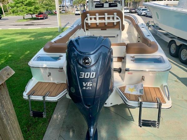 2025 Pioneer 222 Islander boat with 300 V6 engine, docked with lush greenery in background.