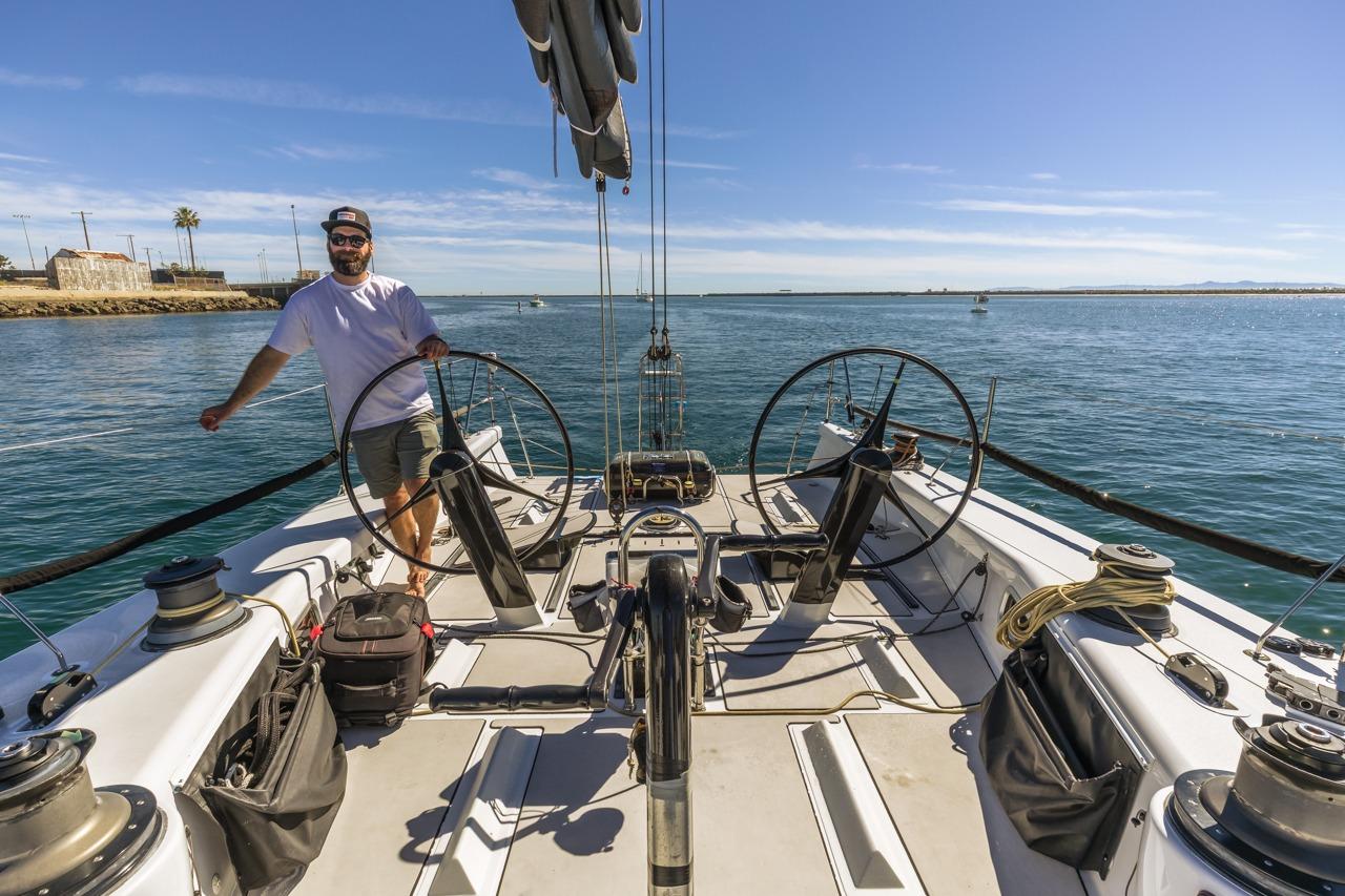 Man steering a 2007 Rogers 46 sailboat on a sunny day at sea.