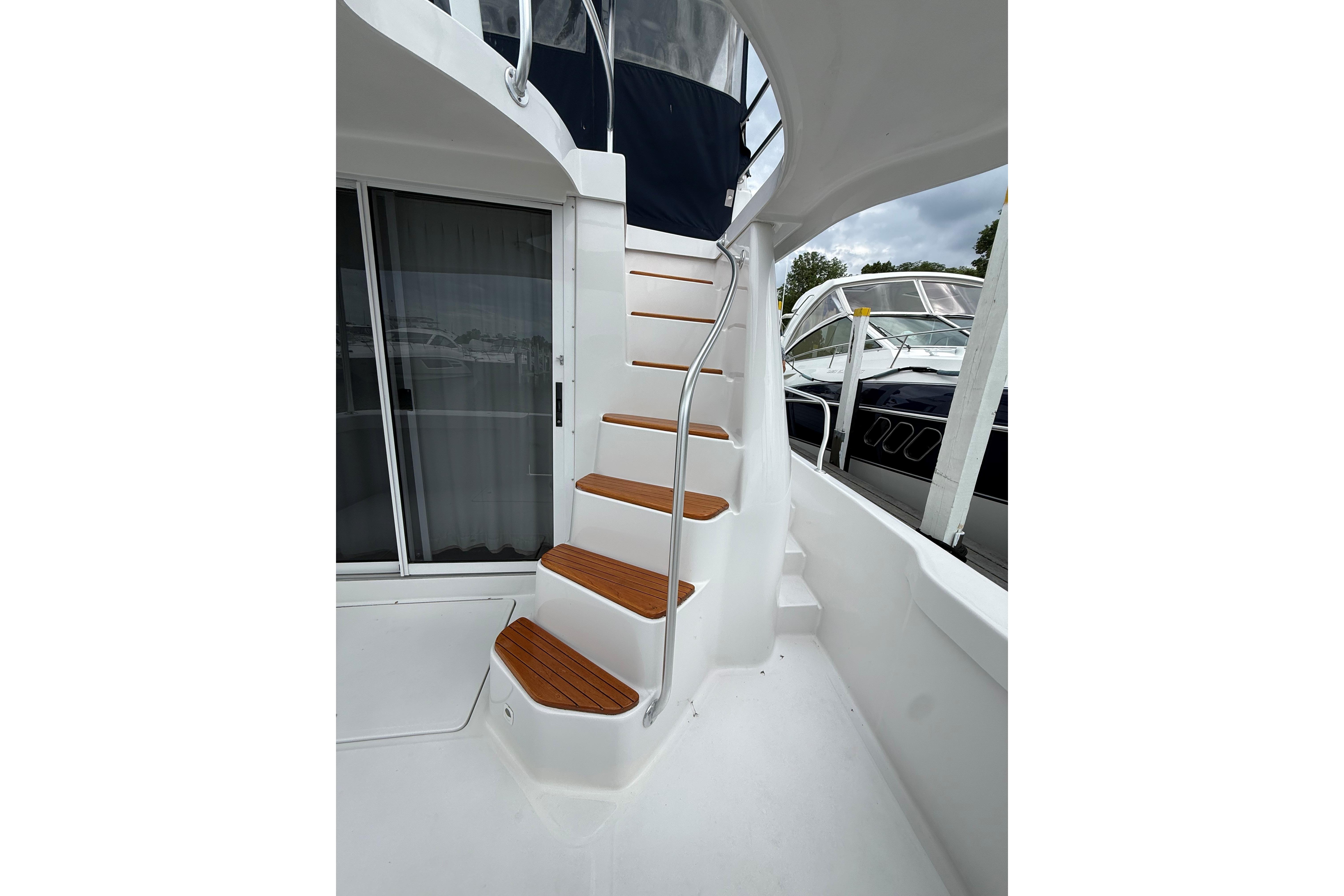 Staircase on 1999 Mainship 350 Trawler with wooden steps and metal railing.