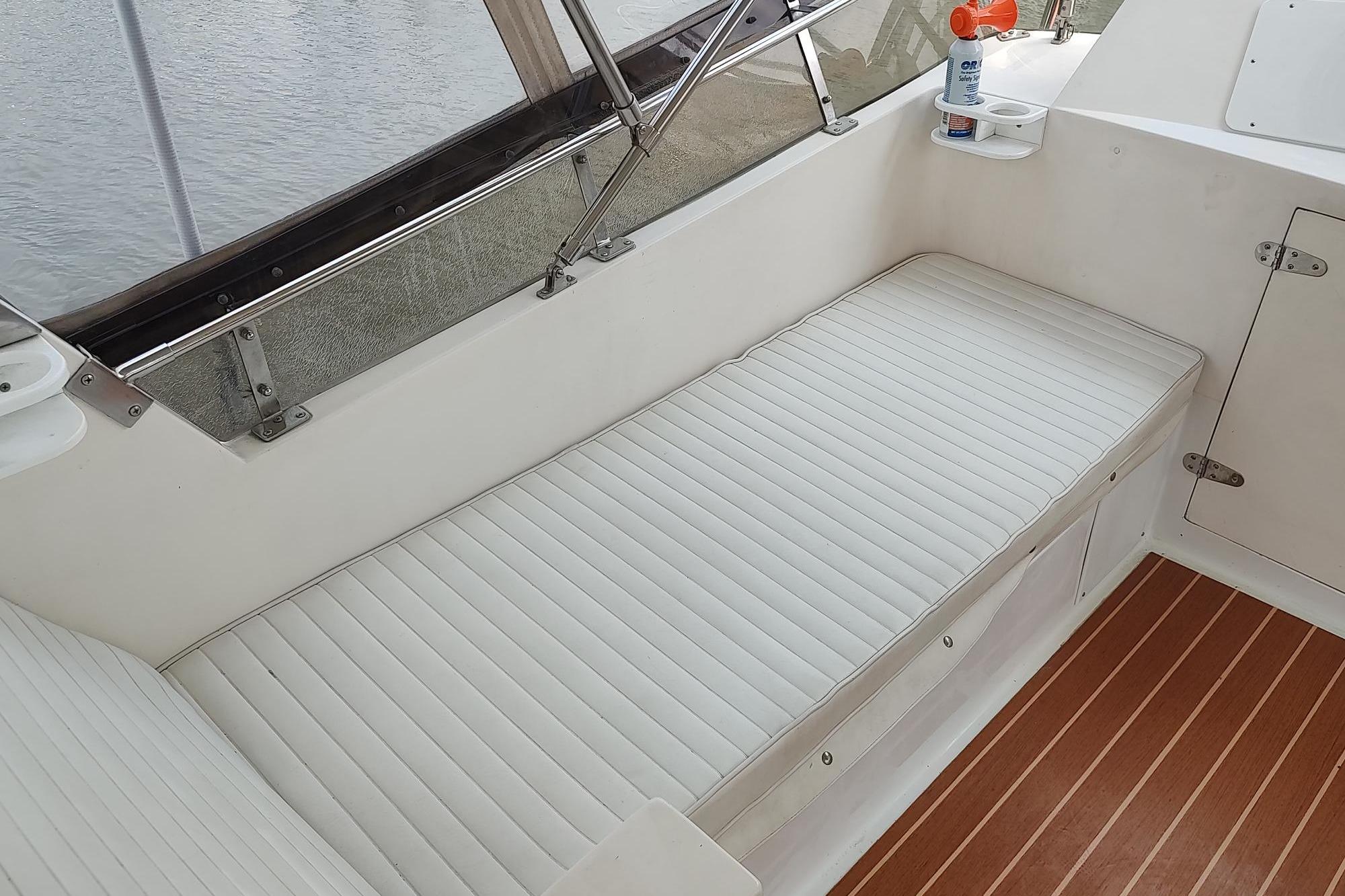 1989 Hyatt Double Cabin Motoryacht interior with white cushioned seating and wooden flooring.