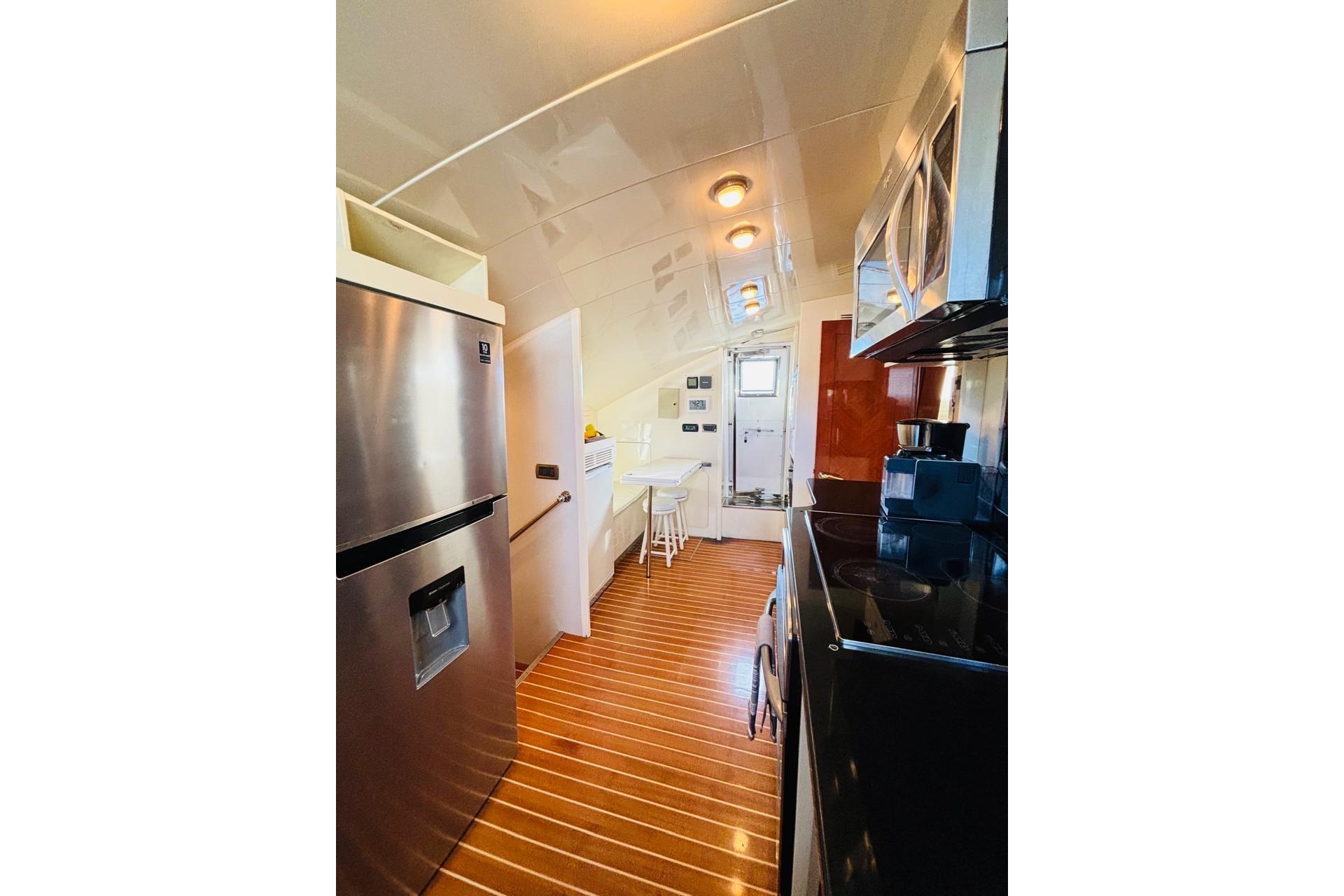 Modern yacht kitchen interior with stainless steel appliances, wooden flooring, and sleek design, Falcon 100, 2000.