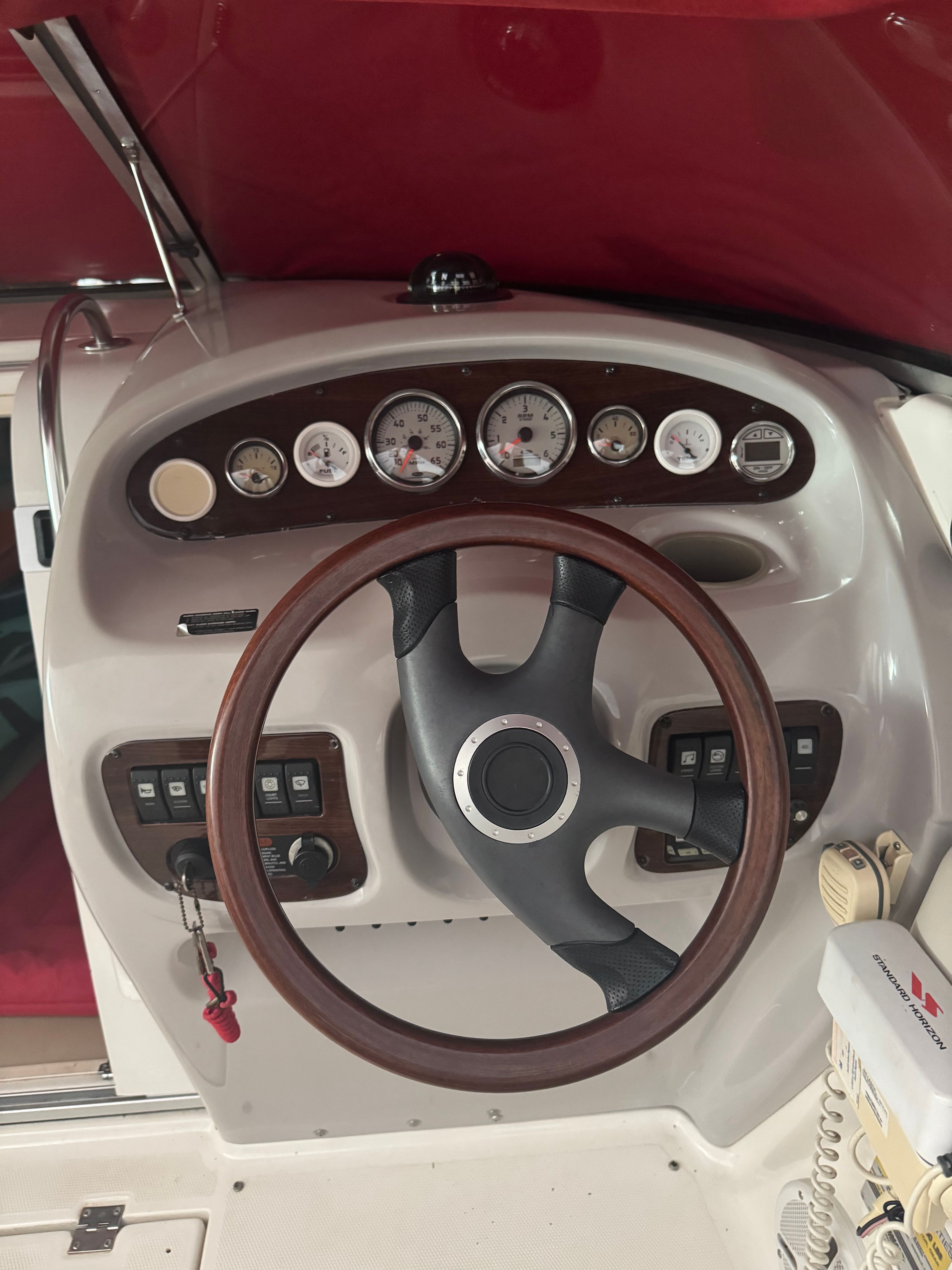 The image shows the cockpit of a 2006 Chaparral 235 SSi with a wood steering wheel and instruments.