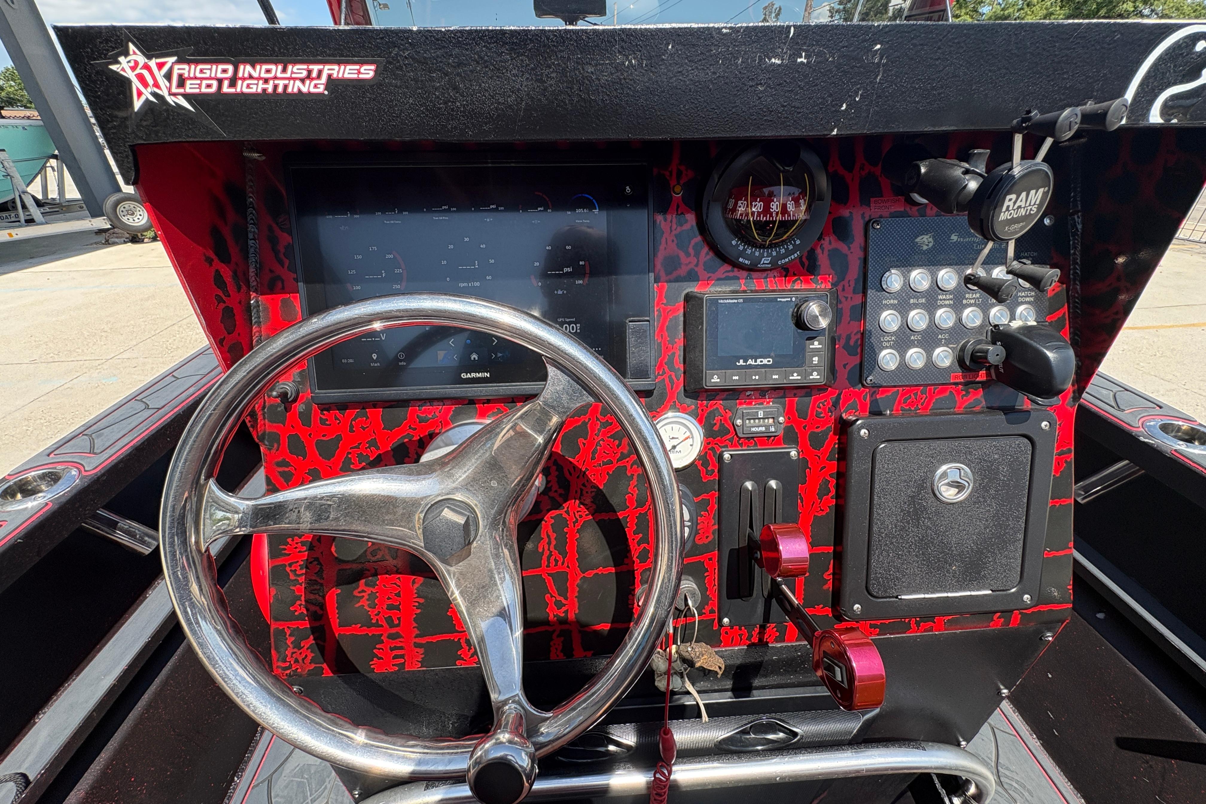 Control panel of a 2018 Custom Swamp Shark 24' boat with red accents and steering wheel.