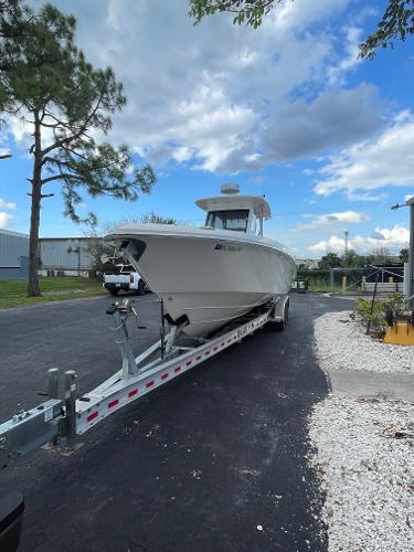 2014 Everglades 325 Center Console boat on trailer, parked outdoors under a partly cloudy sky.