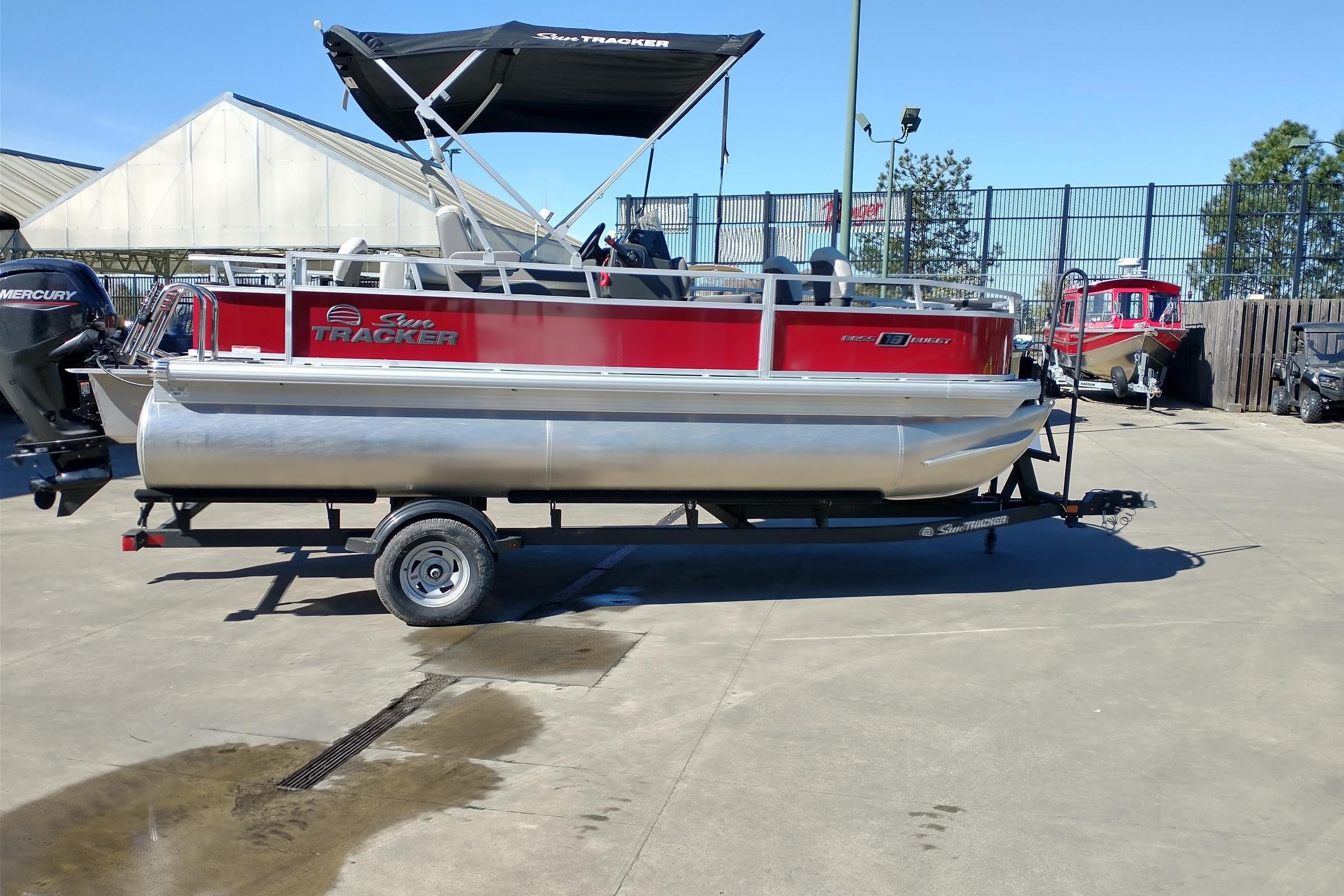 2026 Sun Tracker Bass Buggy 18 DLX pontoon boat on trailer in outdoor setting.