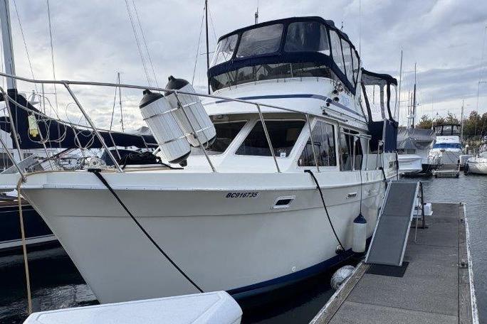 1987 Tollycraft 34 Sundeck Motor Yacht docked at marina under cloudy sky.