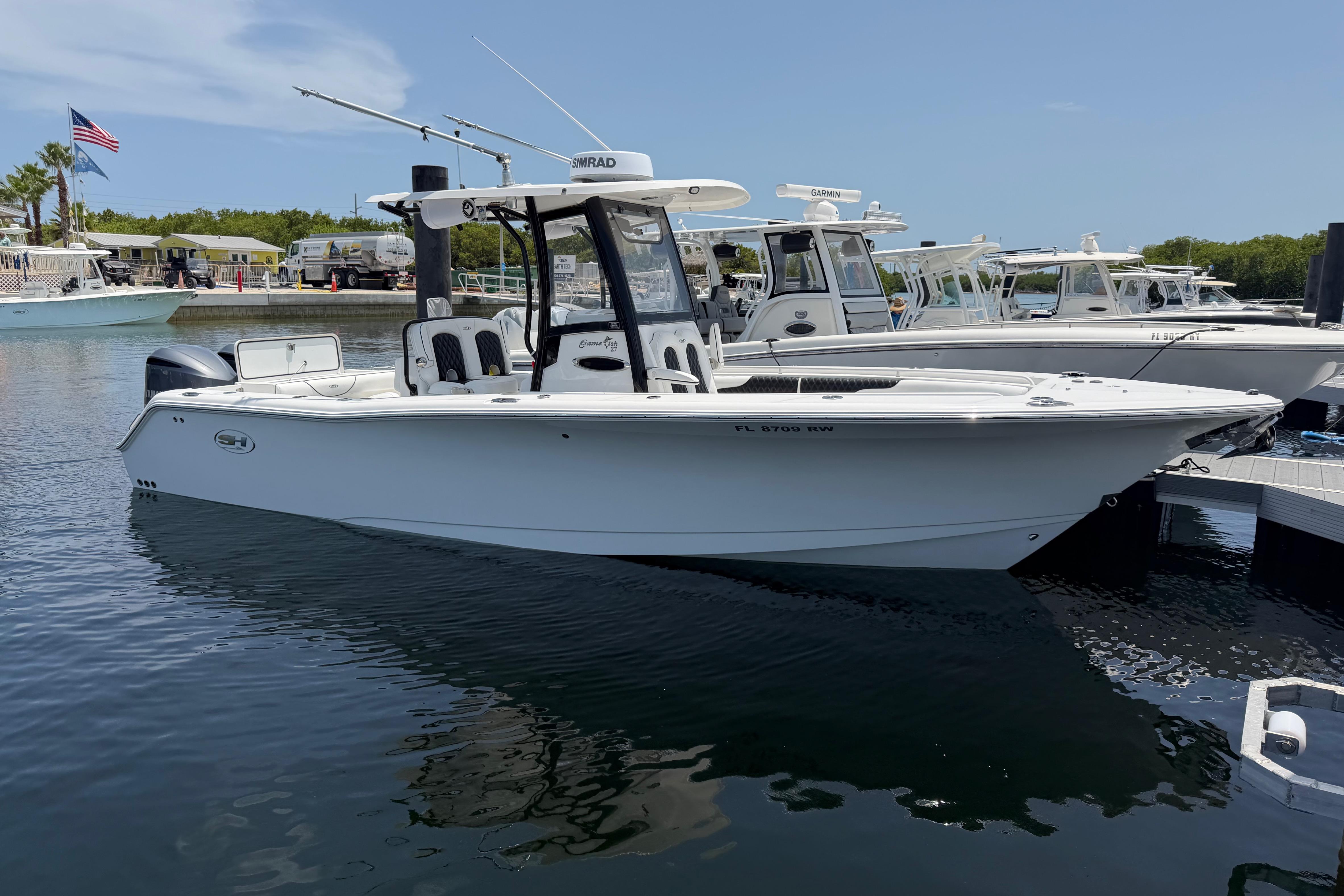2019 Sea Hunt Gamefish 27 Coffin Box boat docked in a marina under clear skies.