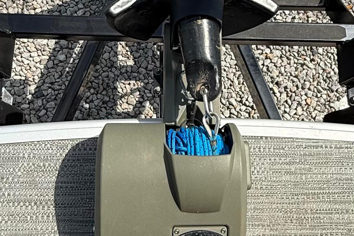 Close-up of 2022 Godfrey SWEETWATER 2486 boat hitch with blue rope on gravel.