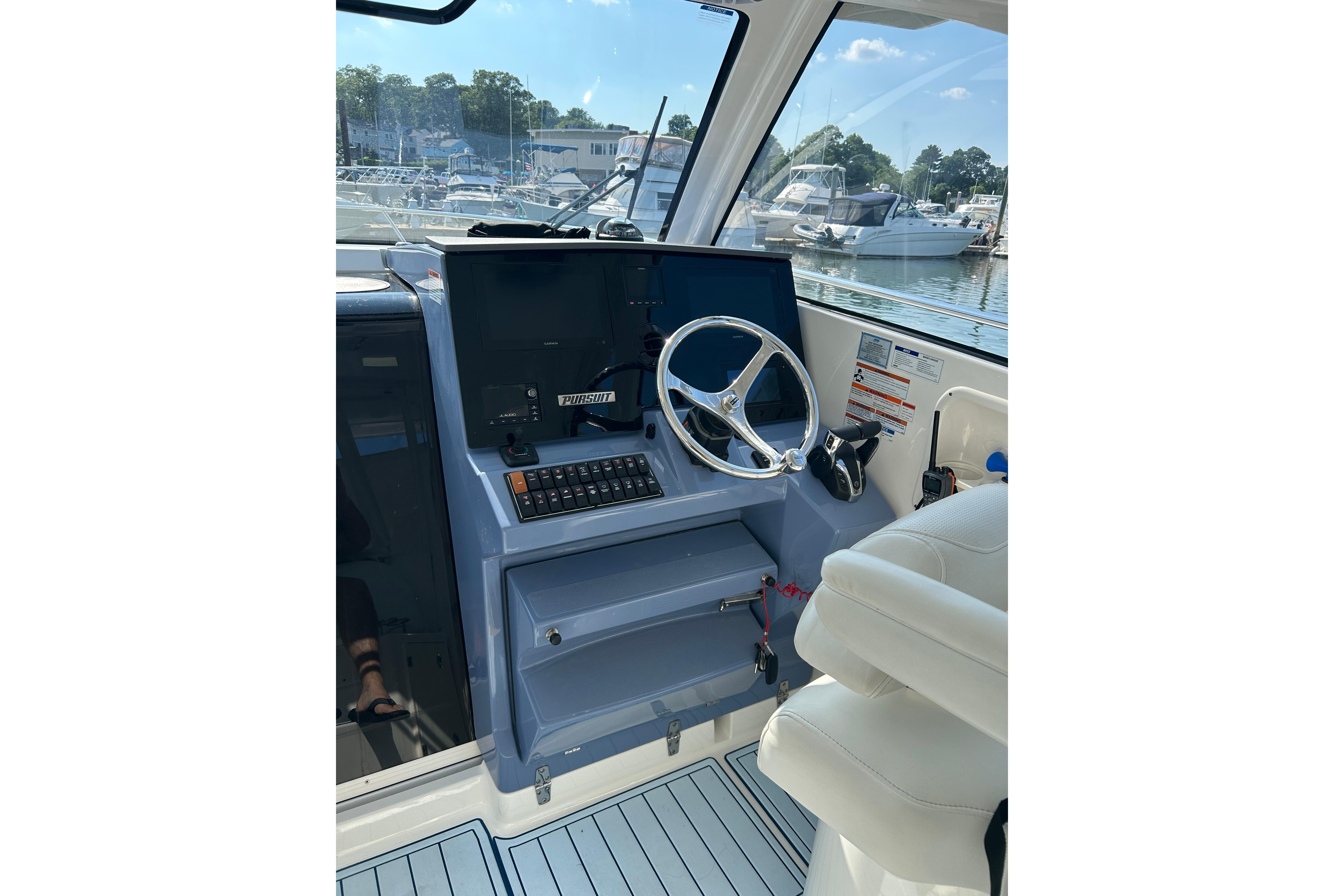 Helm of 2021 Pursuit OS 325 Offshore boat with steering wheel and controls.