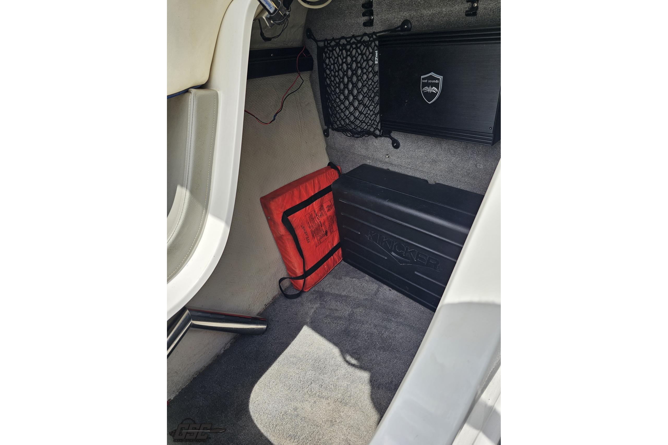Interior of a 2010 Cobalt 232 WSS boat with storage compartment and safety equipment.