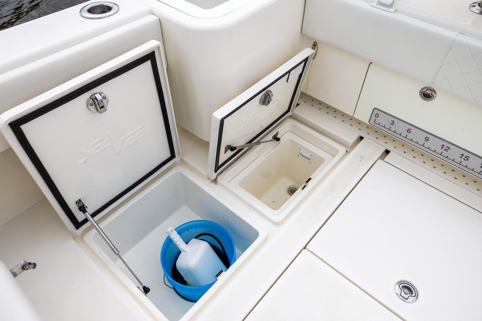 2019 SeaVee 322Z boat storage compartments with open lids and a blue bucket inside.