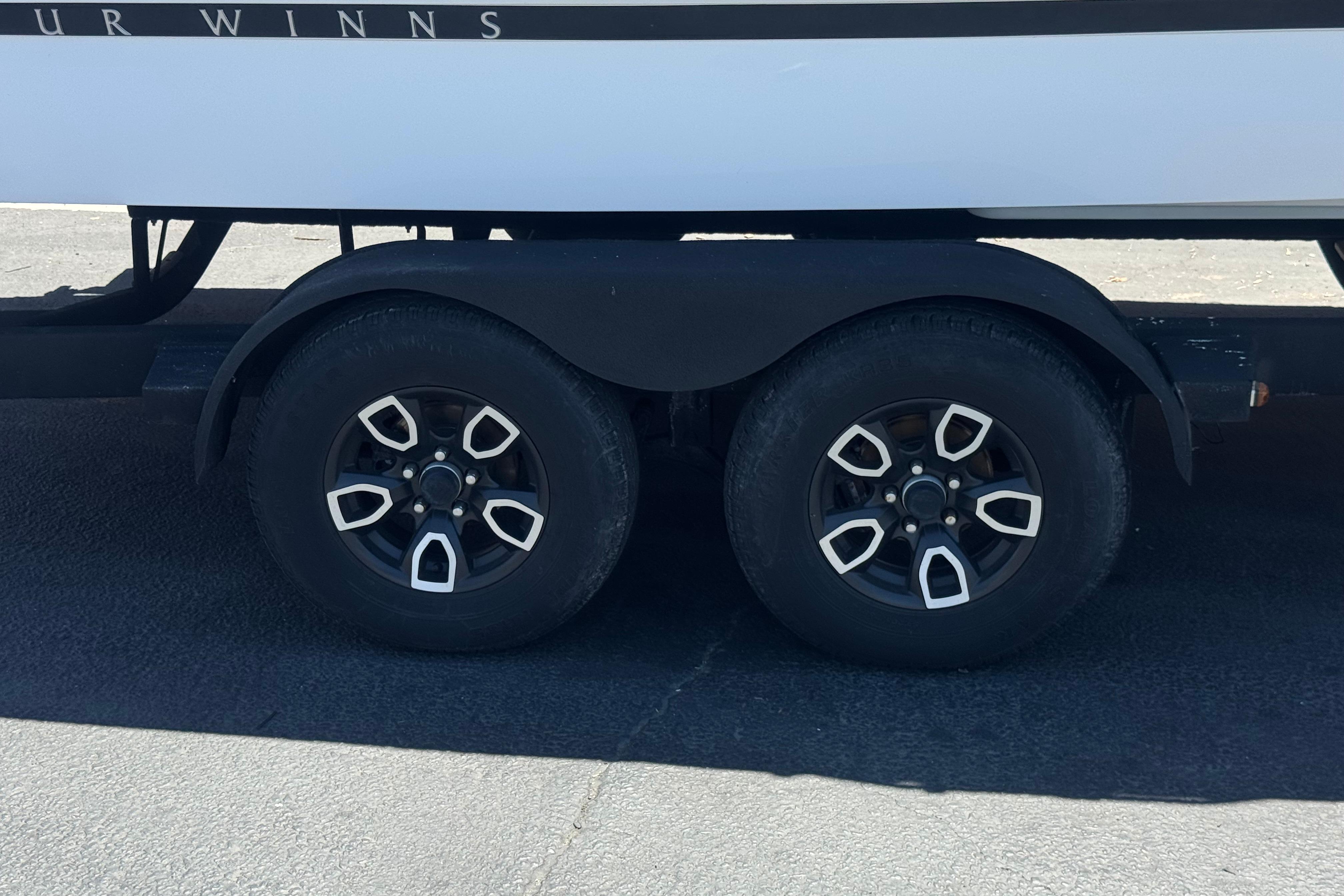 Trailer wheels of a 2022 Four Winns H4 boat on pavement.
