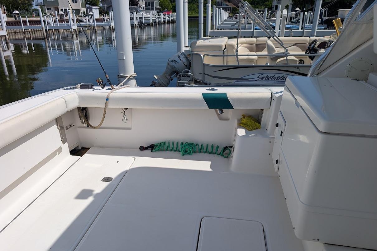 2000 Pursuit 3400 Express boat interior at marina, featuring fishing rod and coiled hose.