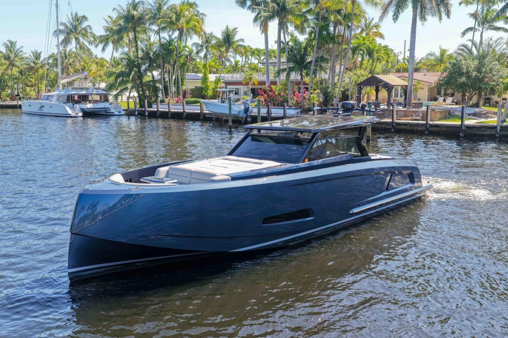 2022 Vanquish Yachts VQ45 luxury yacht cruising on a sunny waterfront with palm trees.