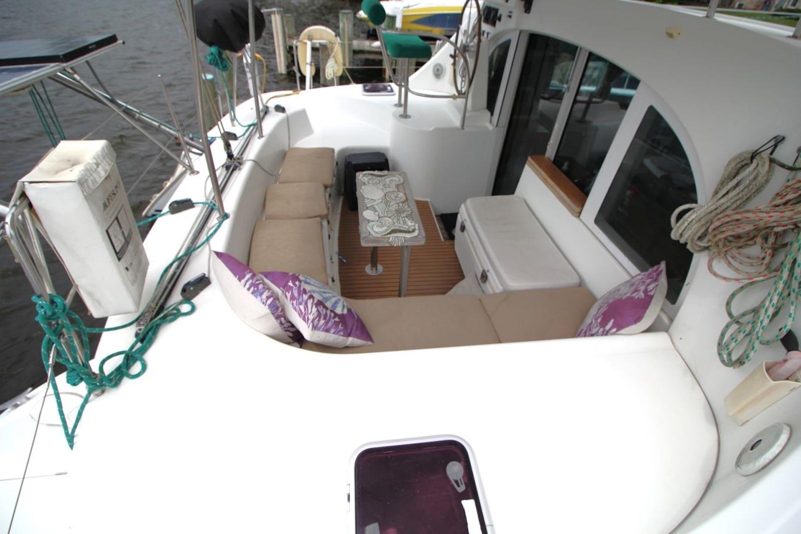 2004 Lagoon 380 catamaran cockpit with cushioned seating, table, and nautical ropes.