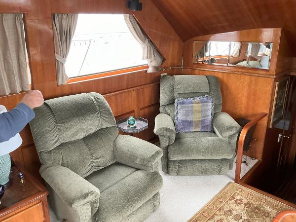 Interior of 2000 Novatec Islander 55 yacht with plush armchairs and wooden paneling.