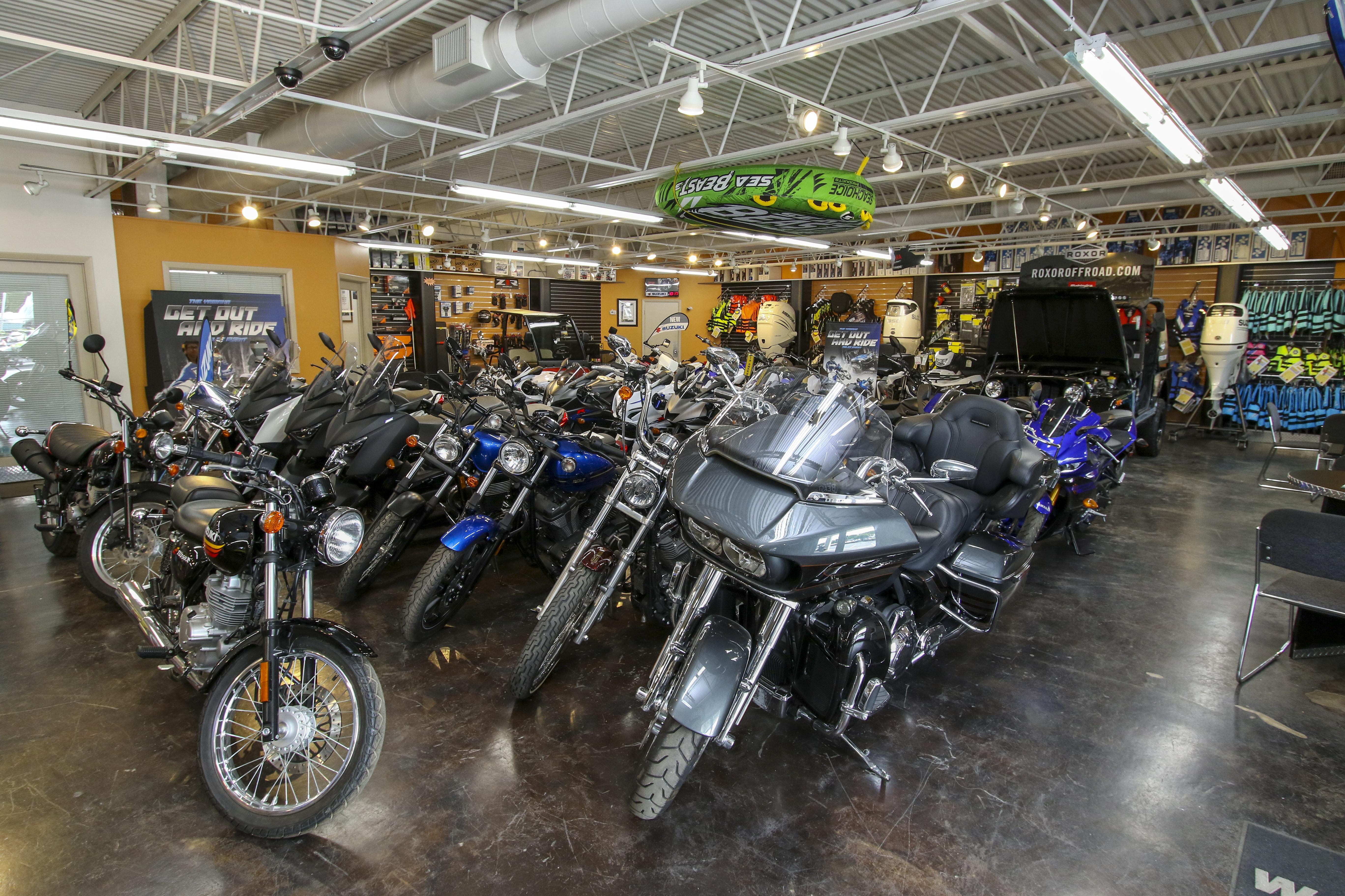 Indoor motorcycle showroom with various models displayed under bright lighting.