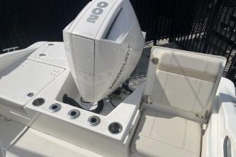 2024 Boston Whaler 220 Dauntless boat with Mercury engine, featuring sleek seating and rod holders.