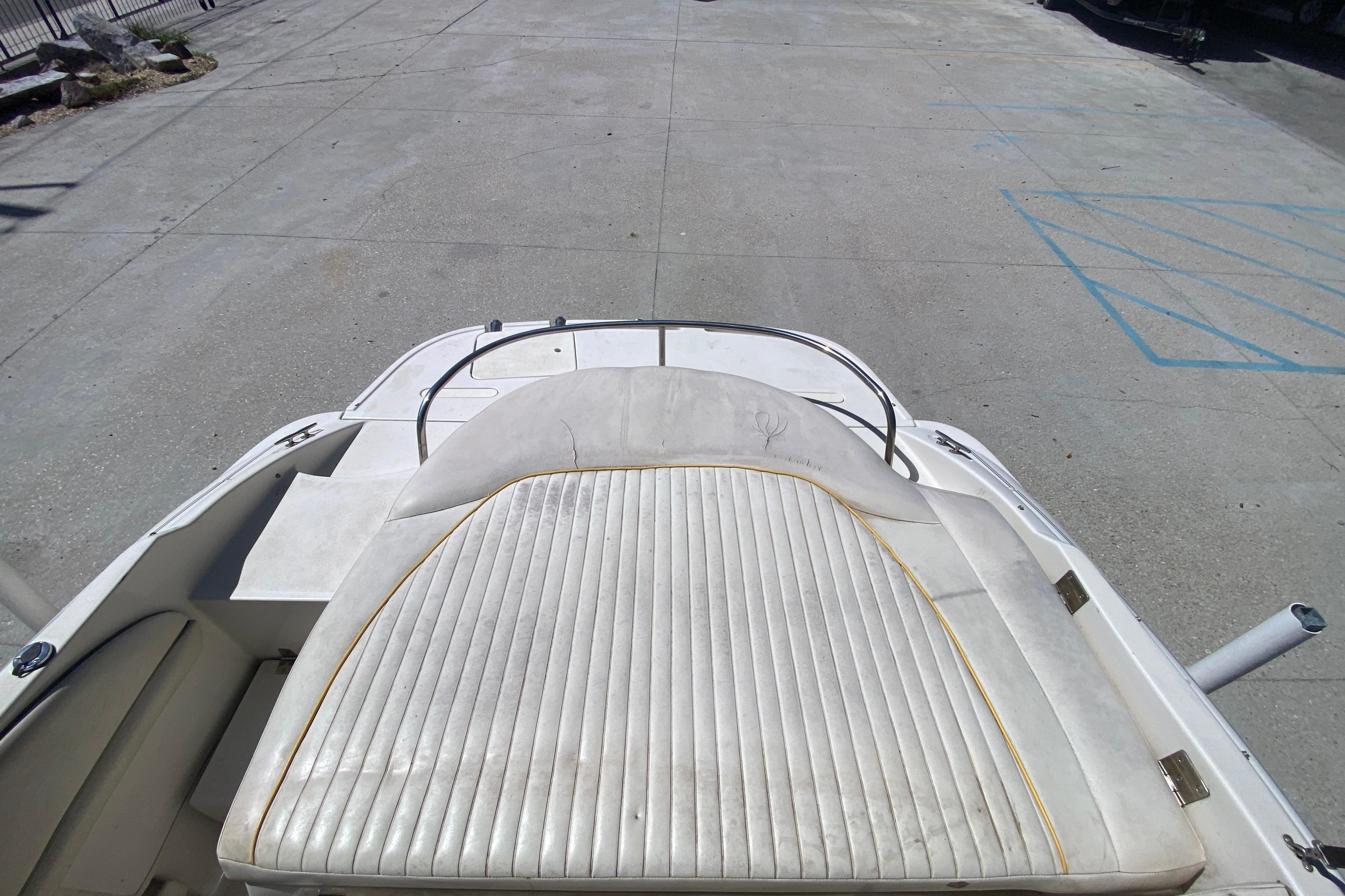 2003 Monterey 208SI Montura boat with white cushioned seating on a concrete surface.