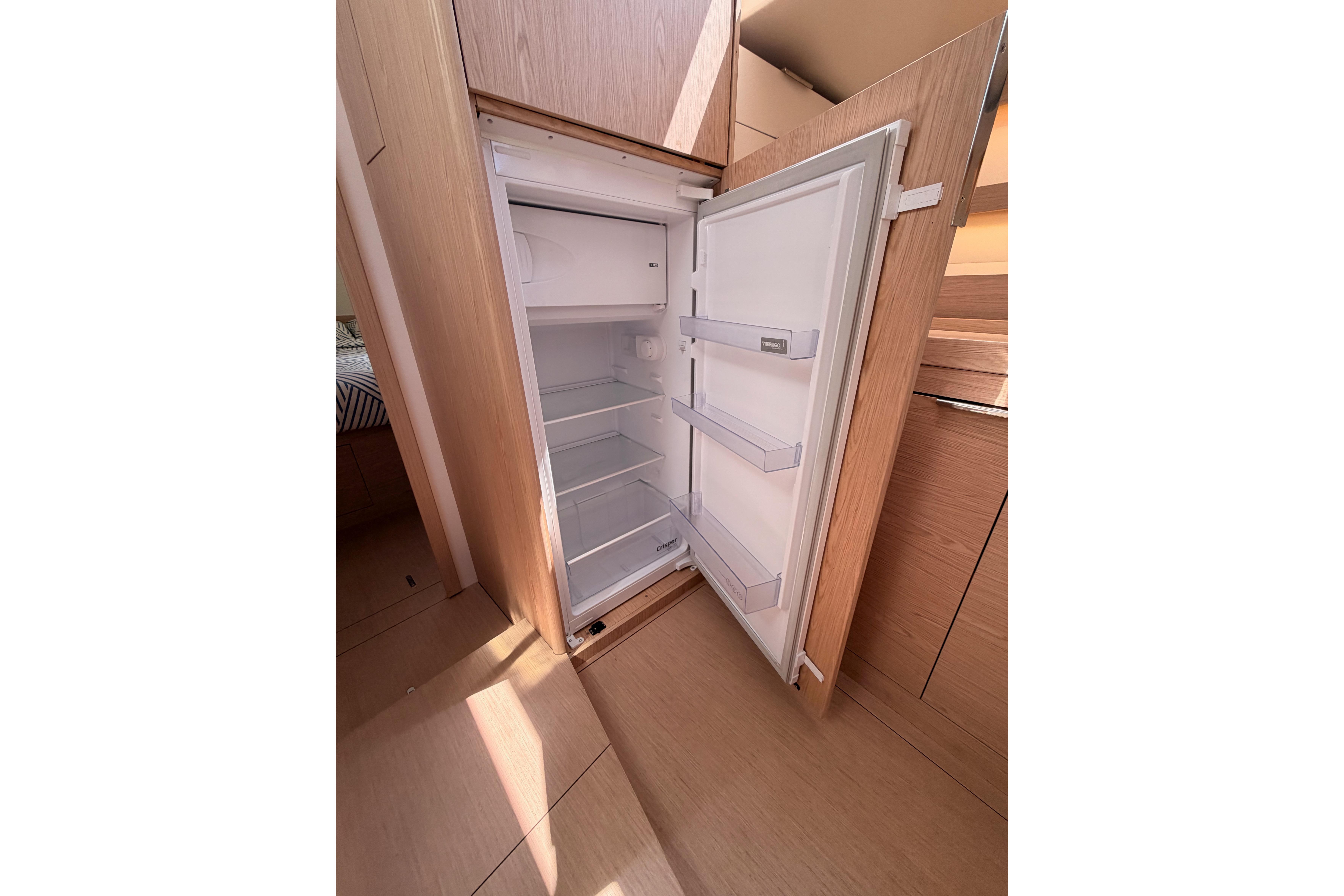 Open refrigerator inside 2022 Beneteau Oceanis Yacht 54, showcasing spacious interior design.