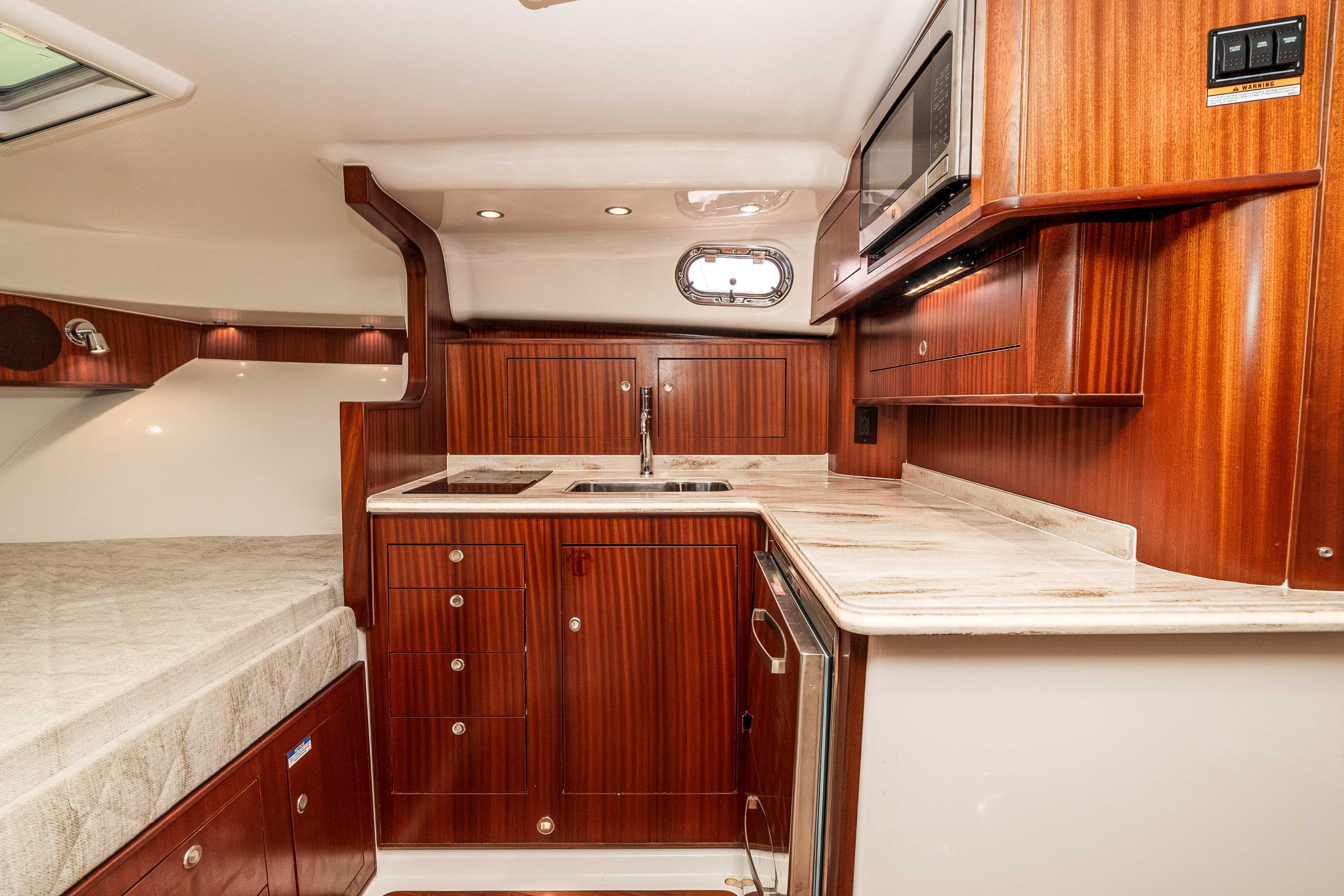 Luxurious 2022 Pursuit OS 385 Offshore yacht interior with elegant wood cabinetry and modern amenities.