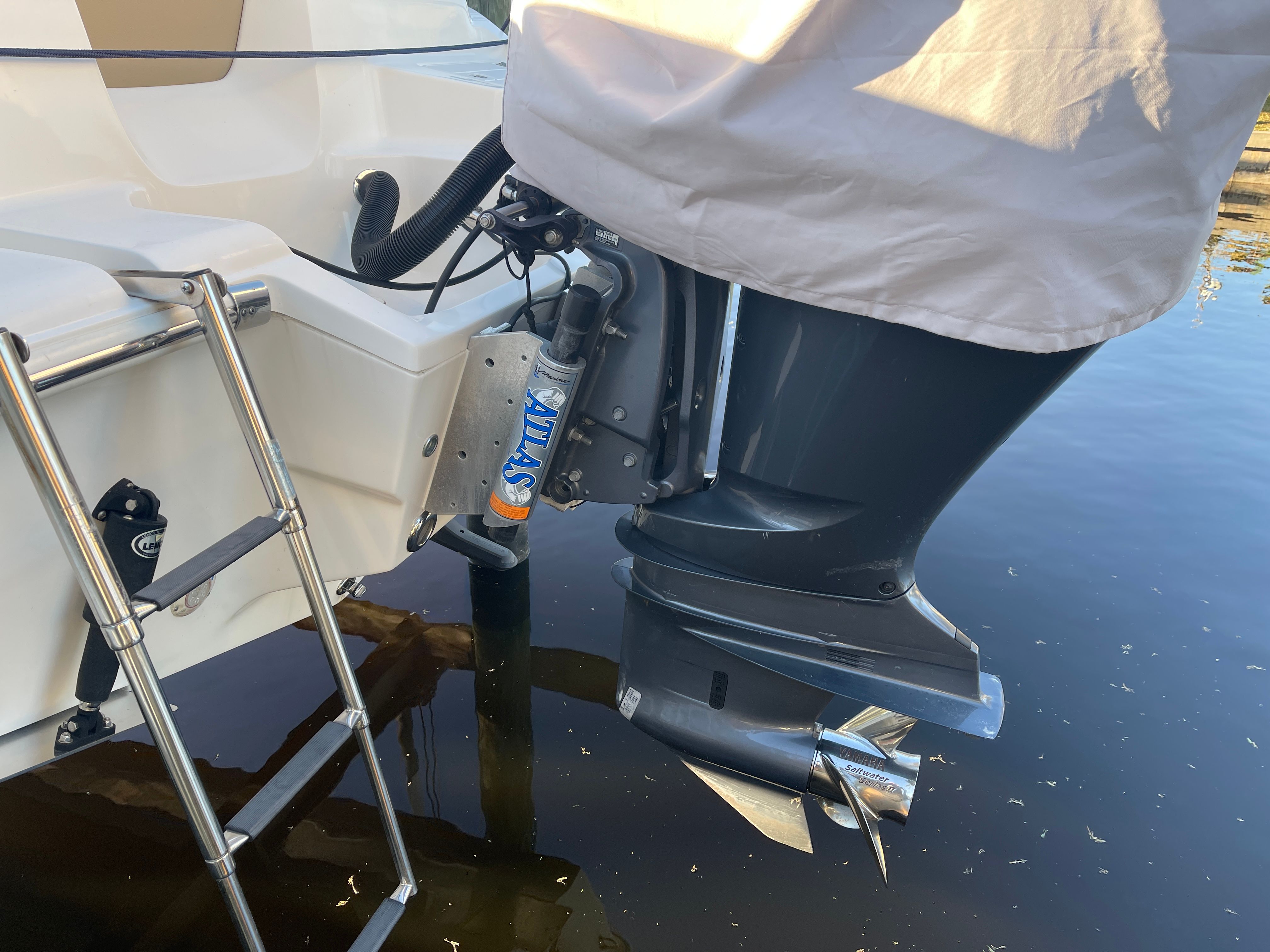 A boat motor with a propeller and a swim ladder are visible at the stern of a boat.