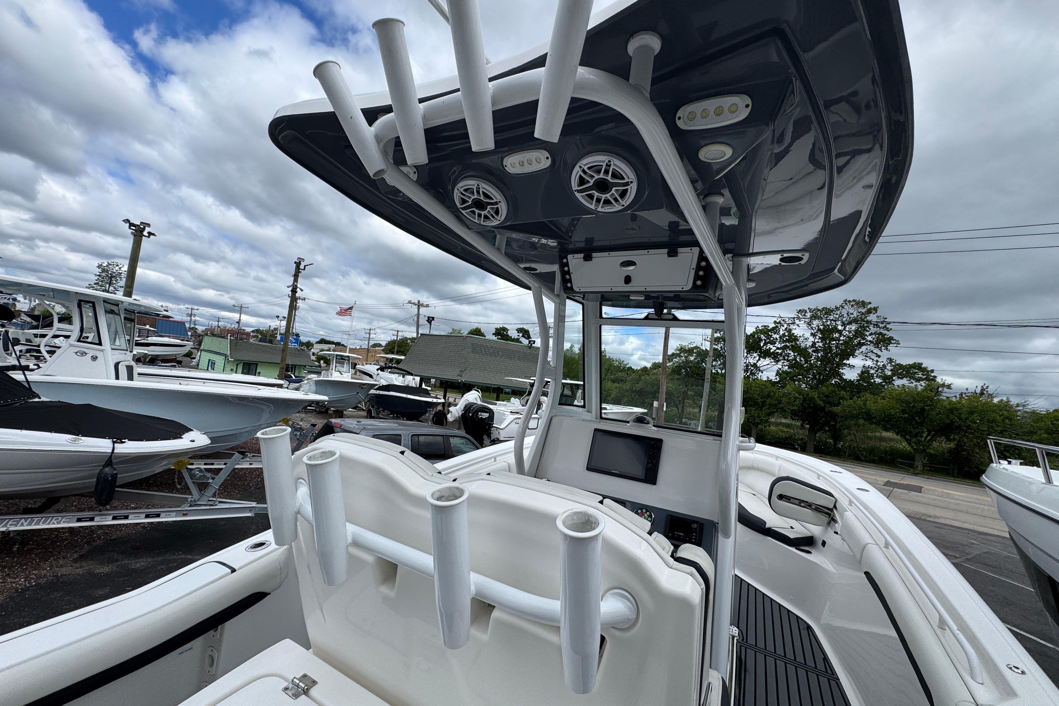2021 Tidewater 280 CC Adventure boat with T-top and rod holders, docked under cloudy skies.