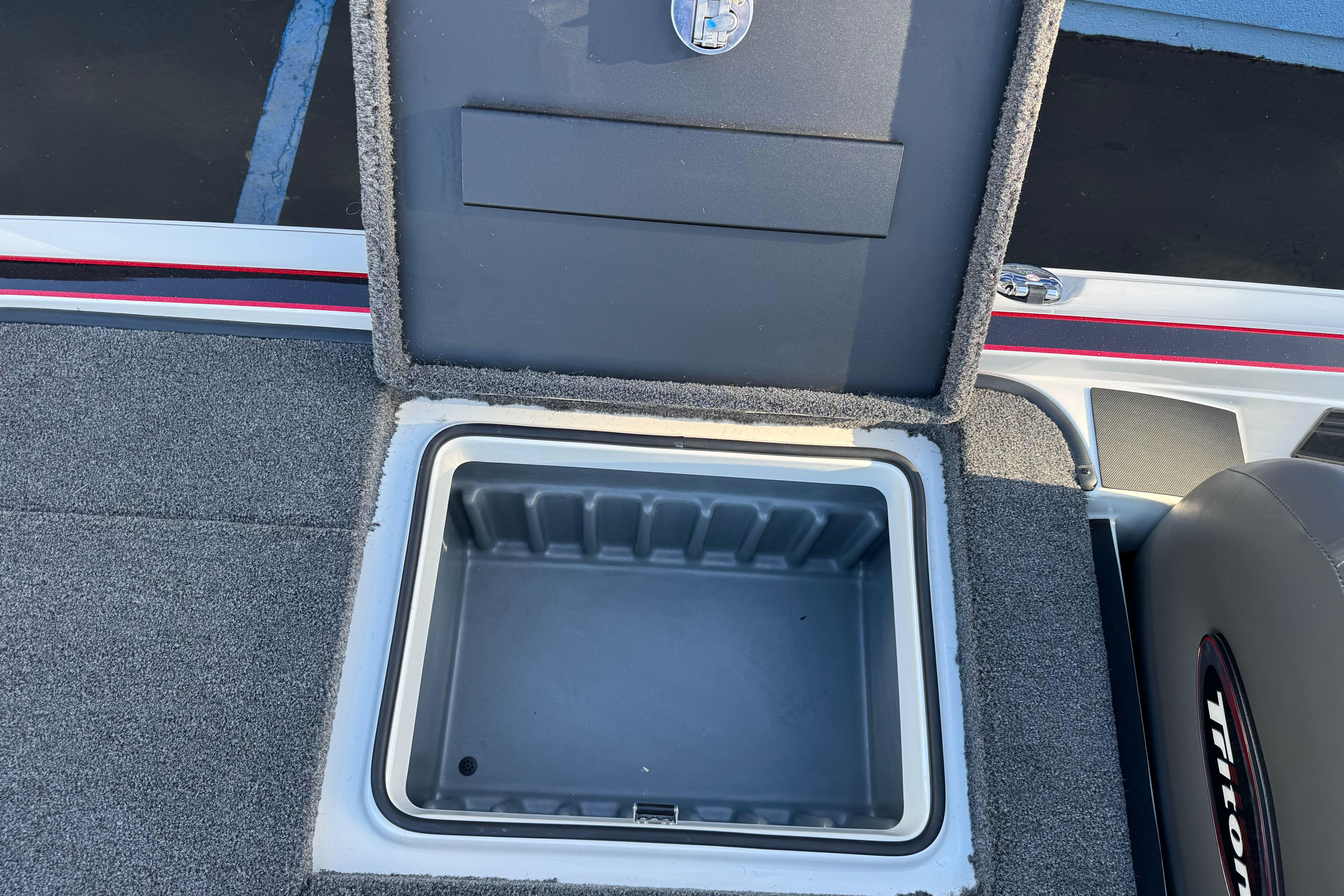 Open storage compartment in 2026 Triton 20XP Patriot boat, featuring carpeted interior.