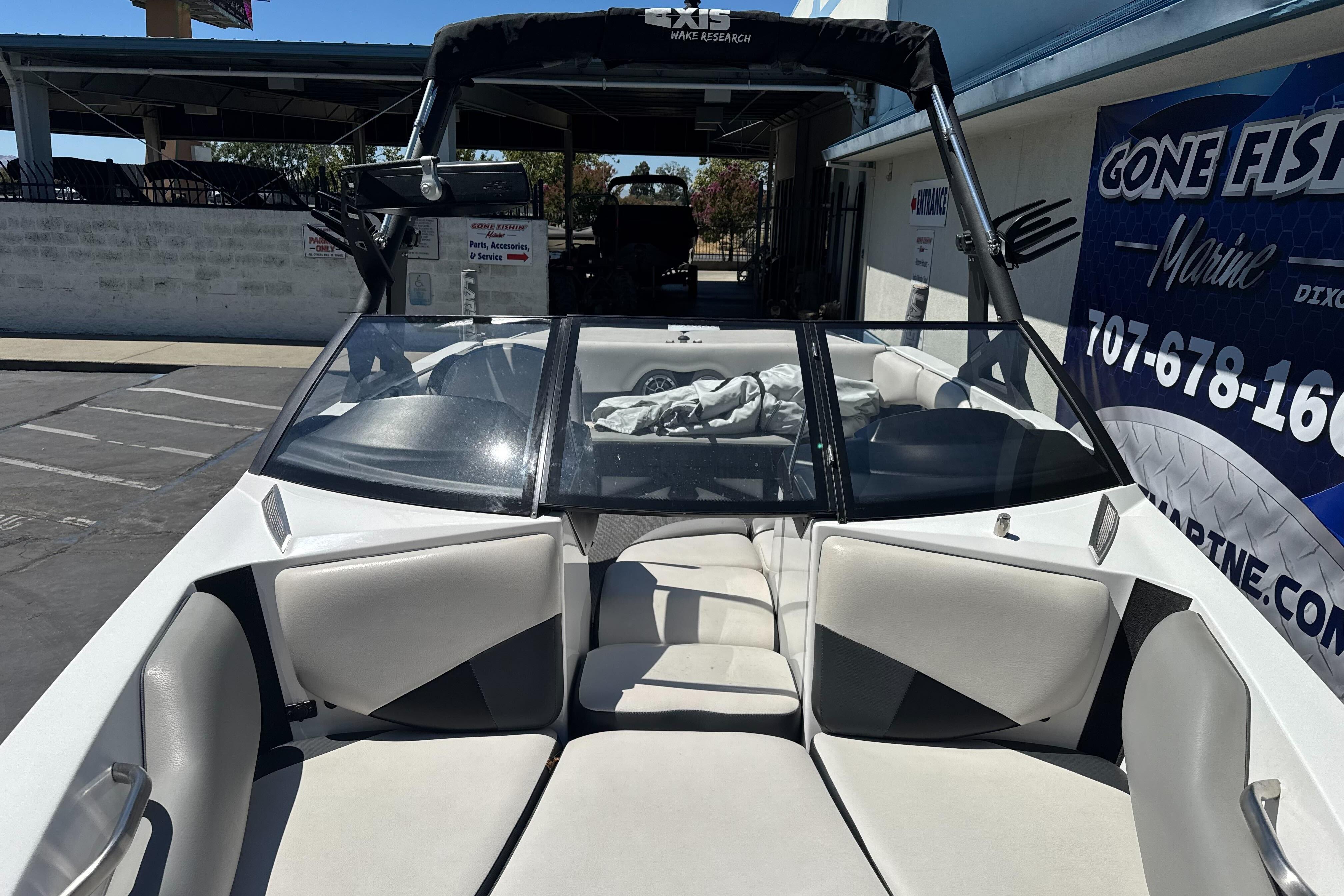 2015 Axis A20 boat with open bow seating, parked near a marine service shop.