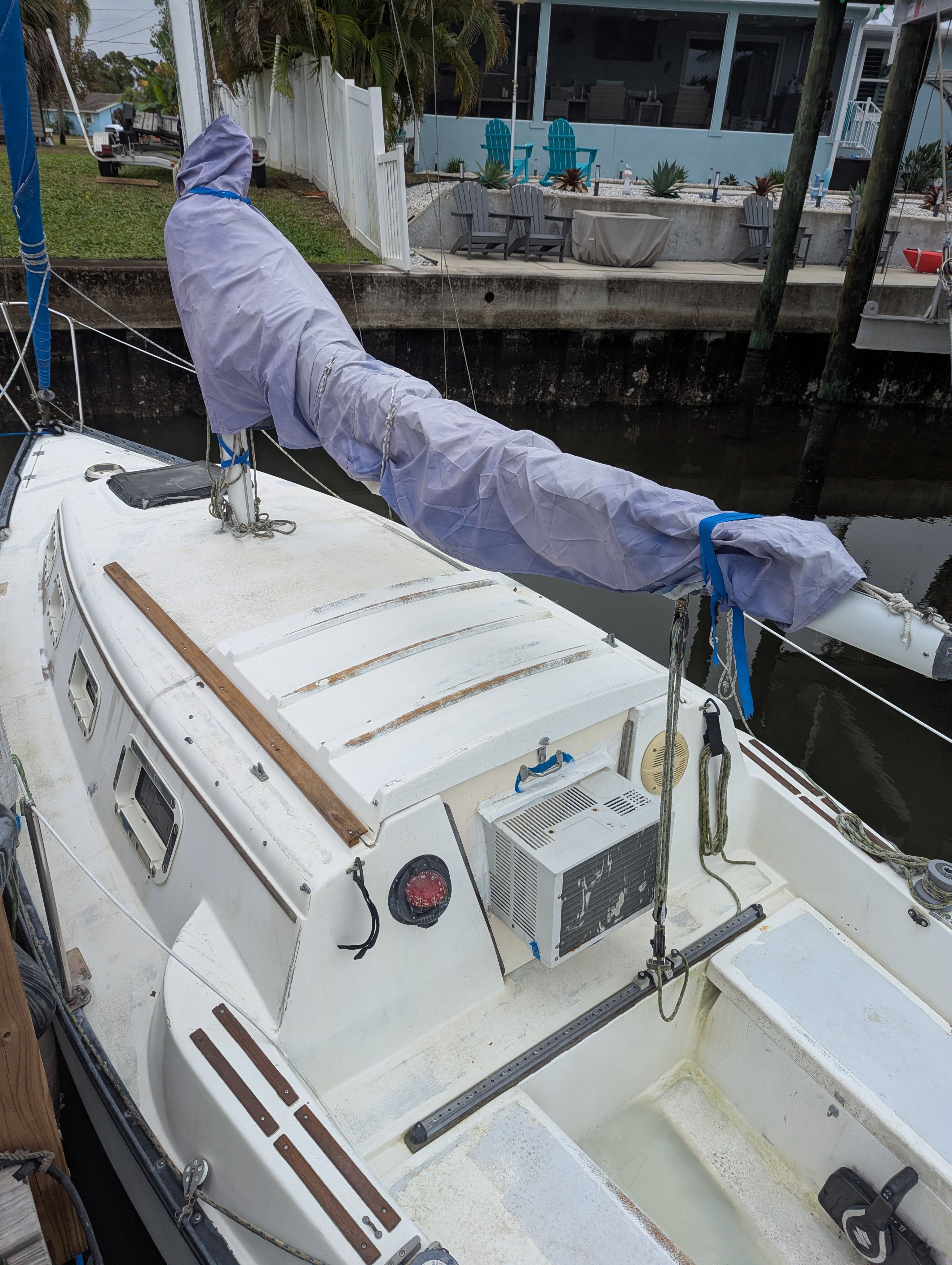 A 1982 Hunter 25.5 sailboat docked, featuring a covered sail.