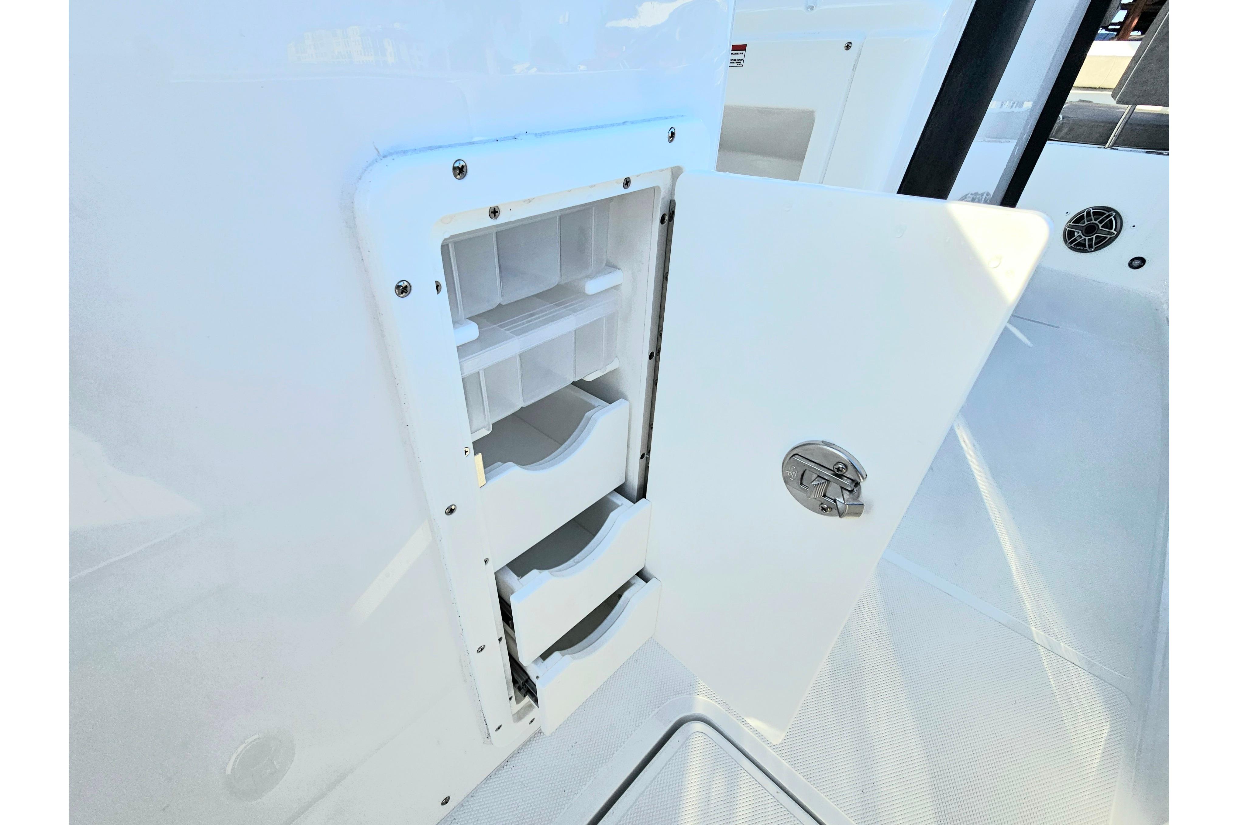 Storage compartment on 2026 Sea Hunt Ultra 285 SE boat, featuring open door and shelves.