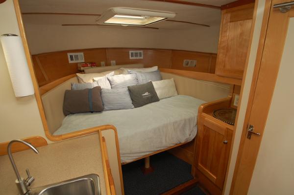 Interior of a 2005 Fox Island Thirty - Sedan Cruiser with cozy bed and wood paneling.