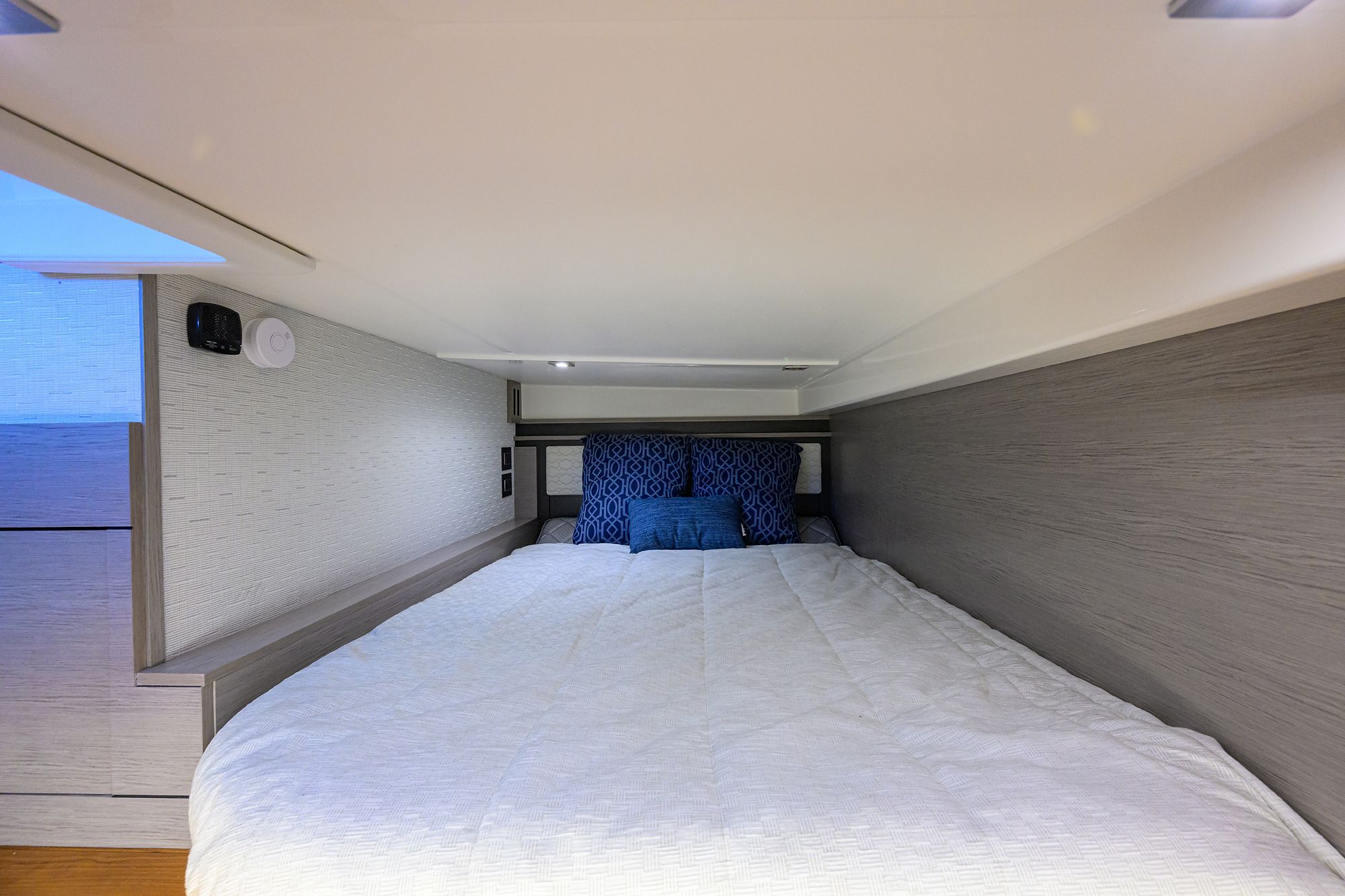 Cabin with a cozy bed and blue pillows on a Tiara Yachts 43 LE.