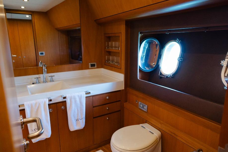 Luxurious bathroom in 2008 Pro Boat Yachts Power Cat 80, featuring wood cabinetry and porthole window.