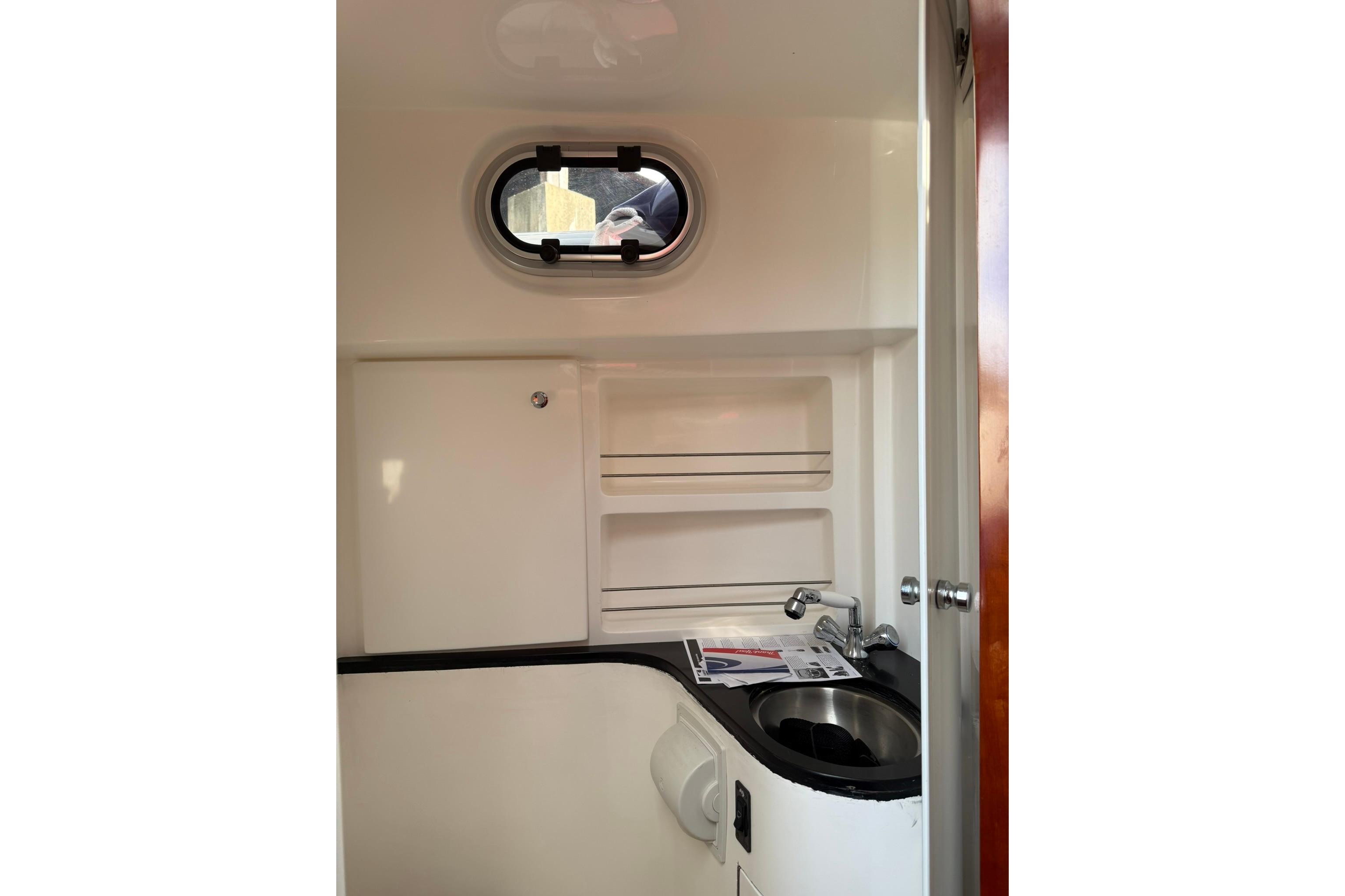 Compact bathroom interior of 2020 SeaPiper 35 boat with sink and porthole window.
