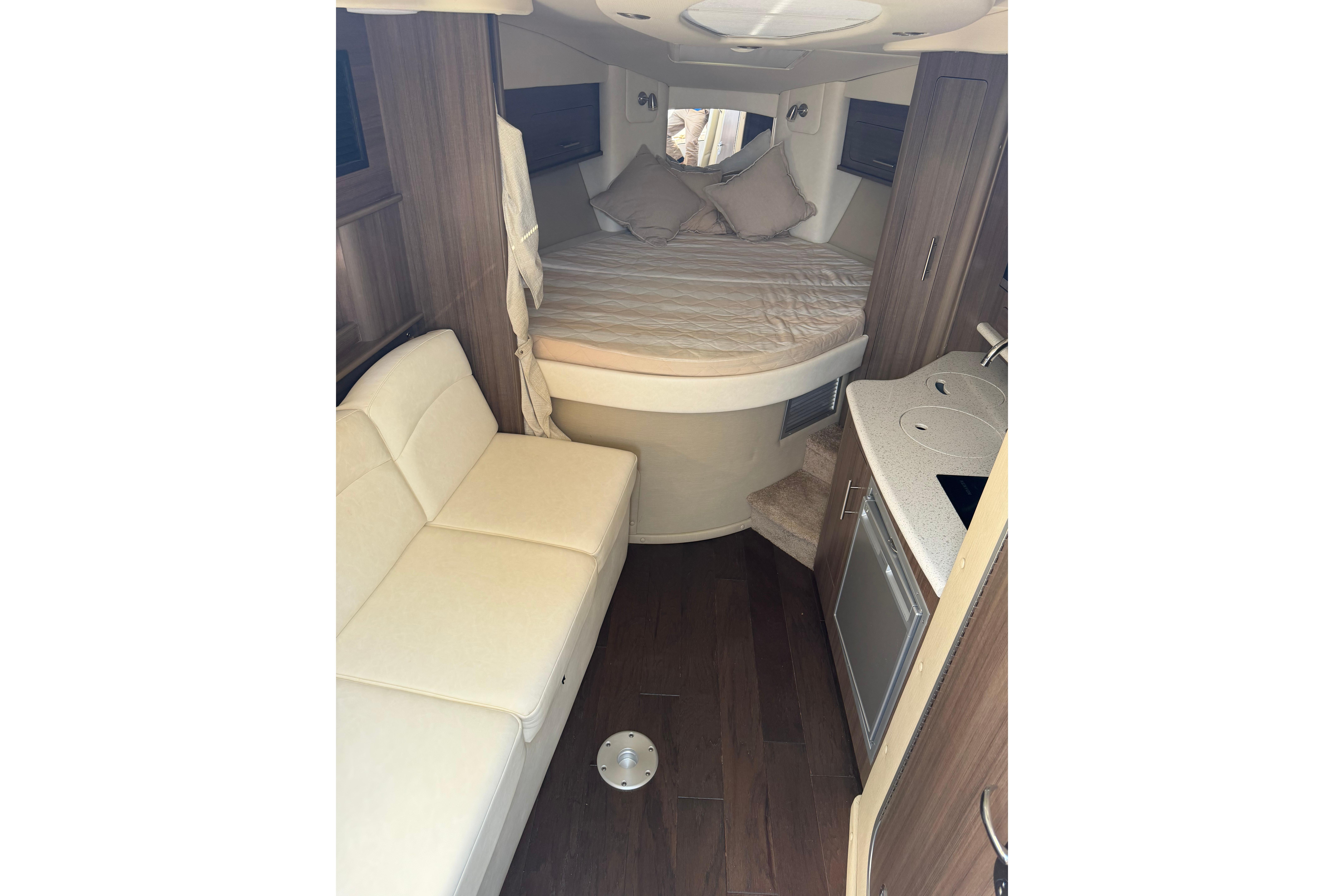 2019 Rinker EX 320 cabin interior with bed, sofa, and kitchenette.