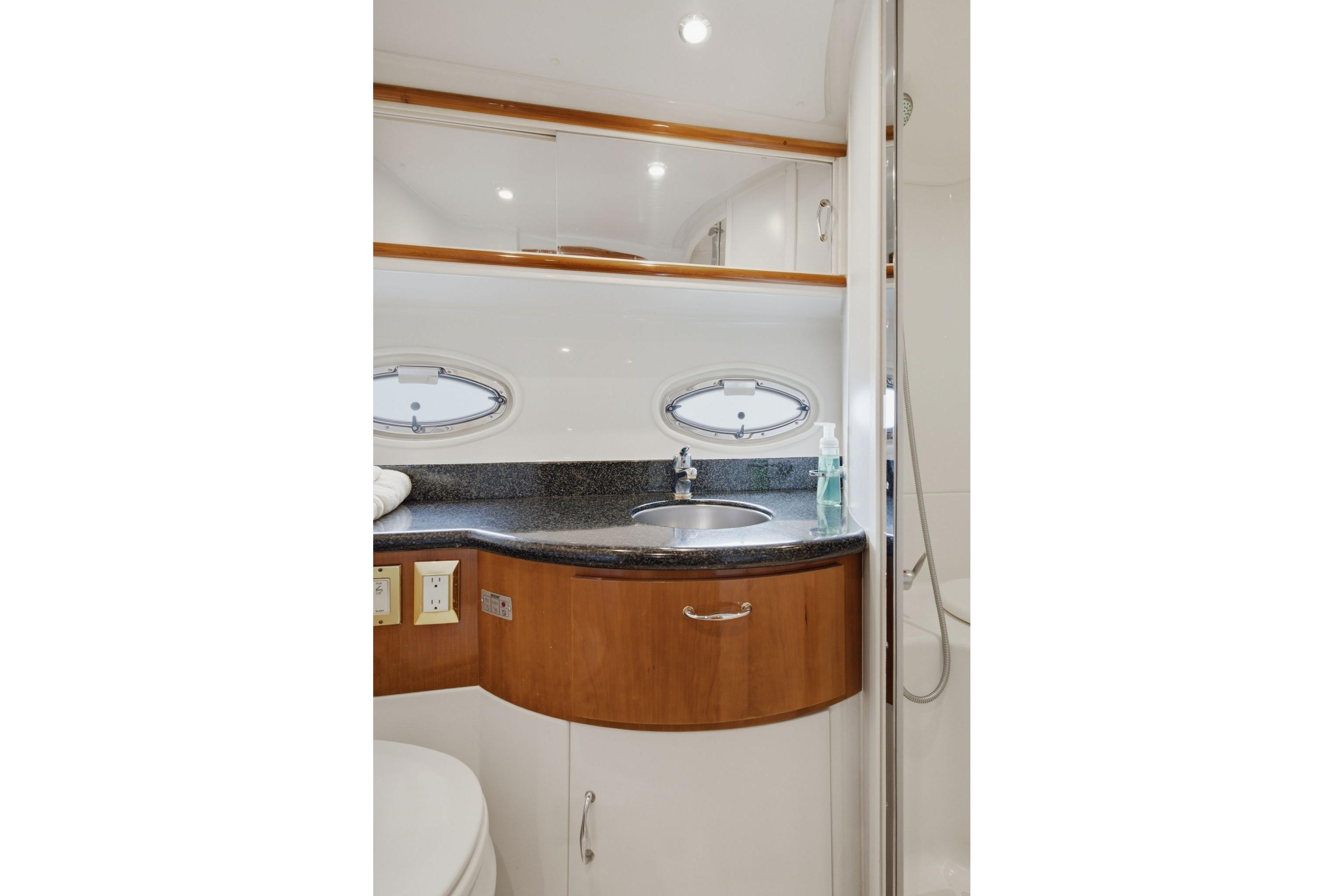 Luxurious bathroom interior of 2005 Carver 39 Motor Yacht with sleek sink and porthole windows.