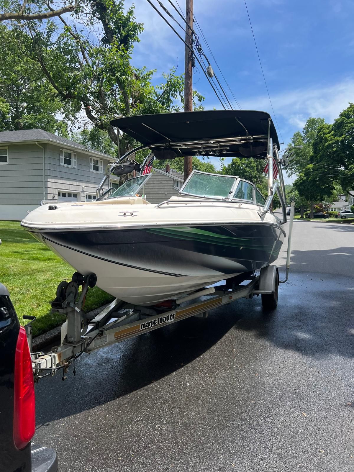 A 1997 Sea Ray 190 Bow Rider on a trailer in a residential street.