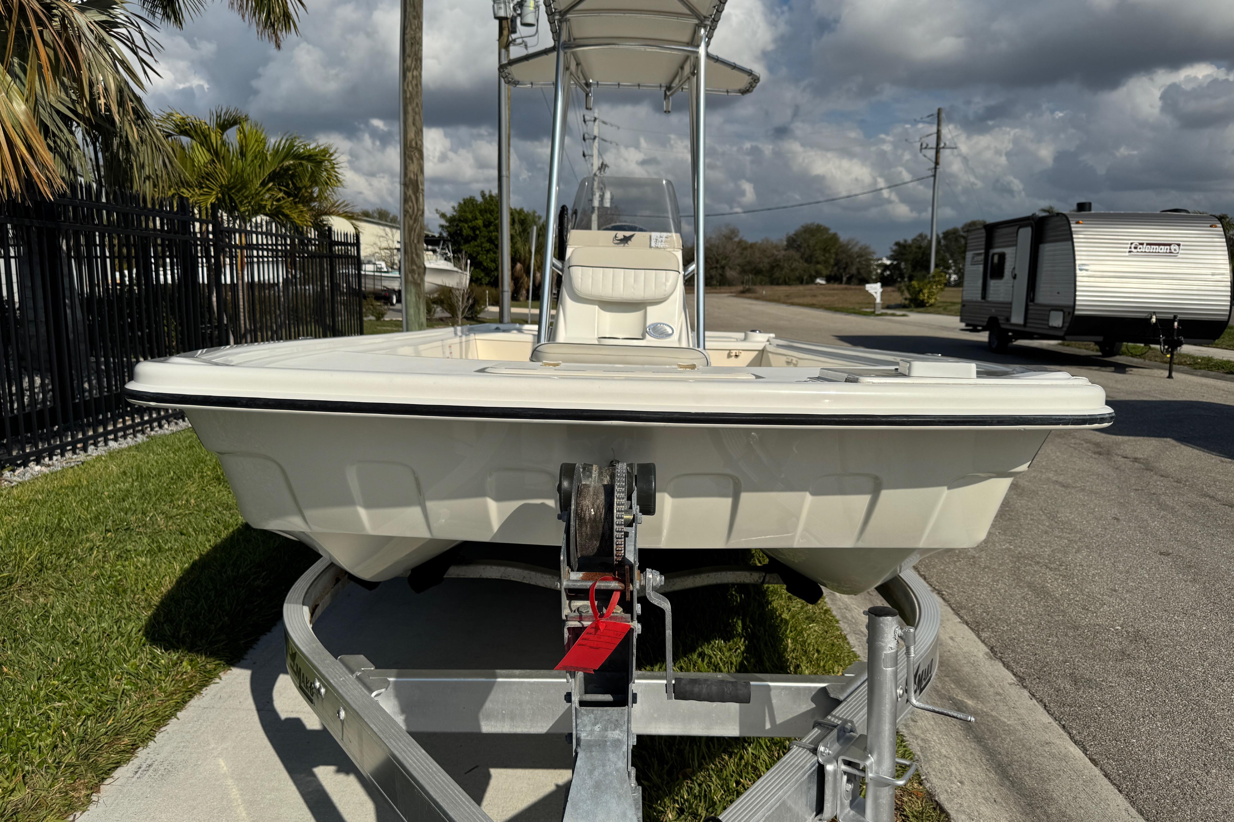 2017 Mako Pro Skiff 19 CC boat on trailer, parked near palm trees and RV.