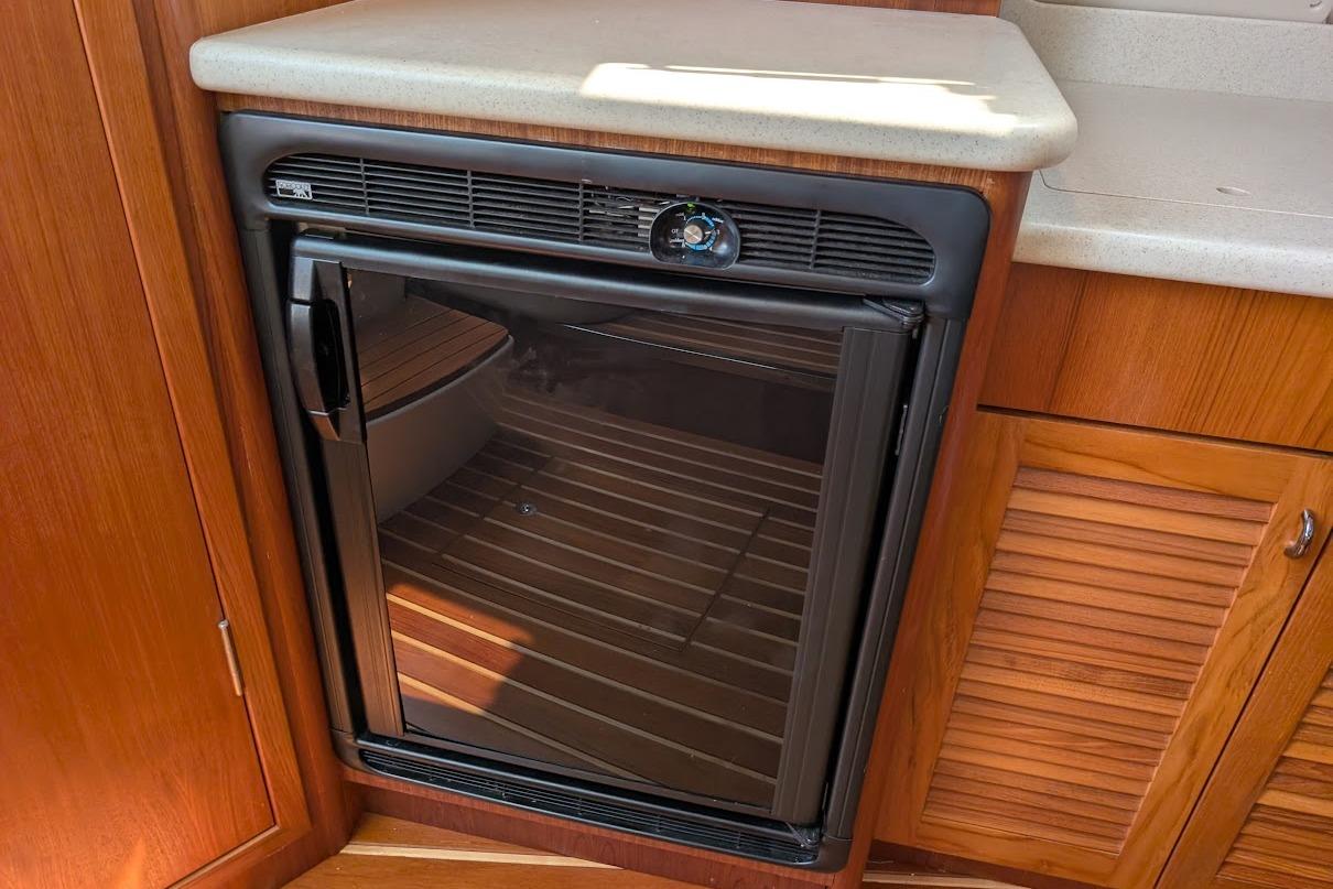 Compact refrigerator in 2000 Pursuit 3400 Express boat interior, featuring wood cabinetry.