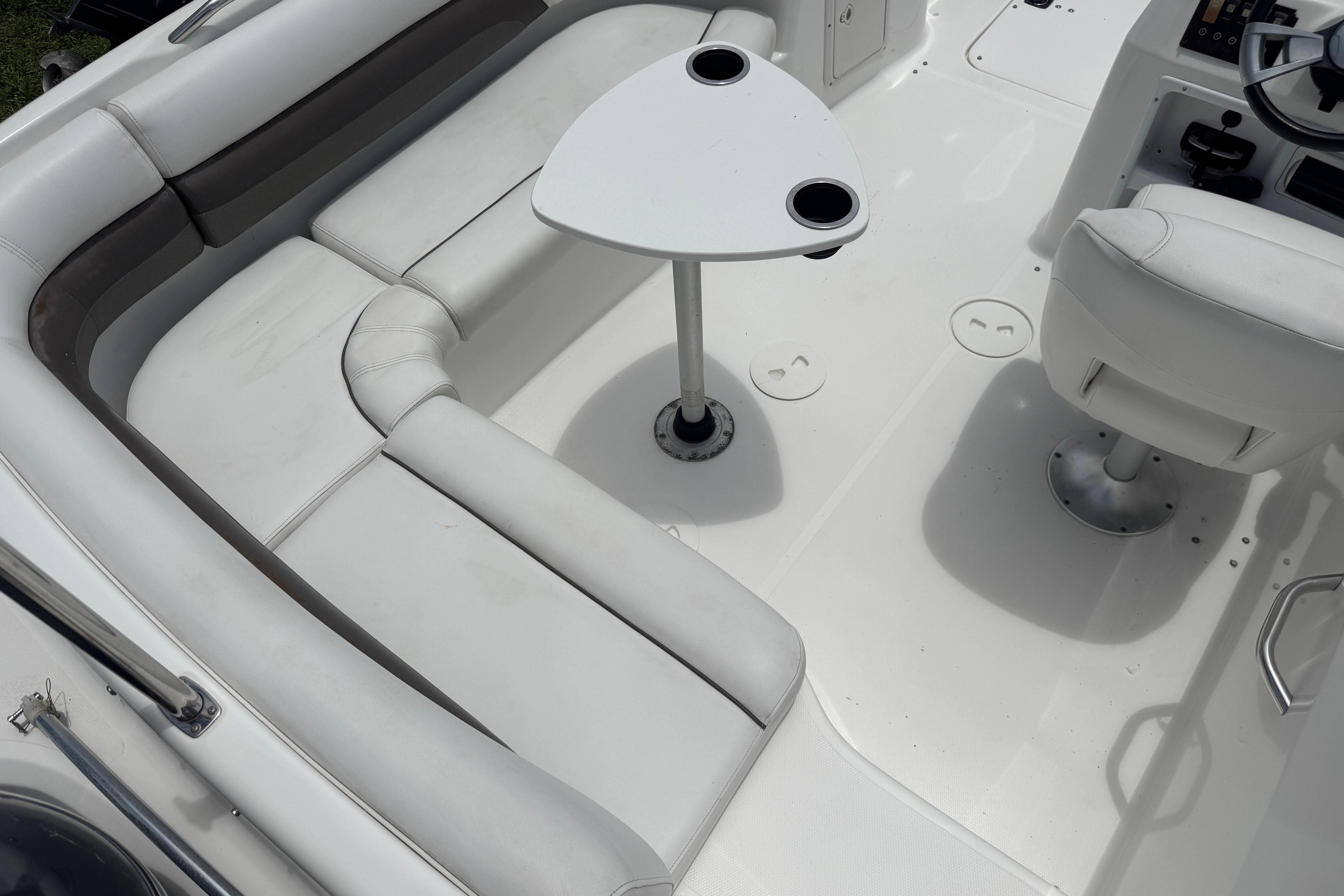 Interior of a 2013 Hurricane SunDeck Sport 188 OB boat with white seating and table.