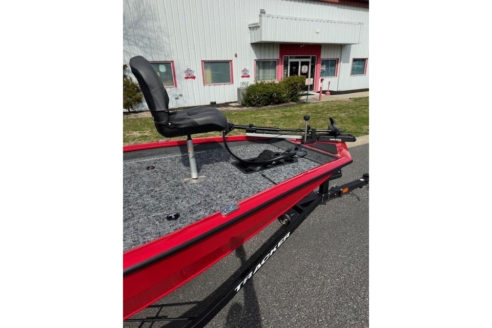 2026 Tracker Pro Team 175 boat with red exterior and fishing seat, parked outside a building.