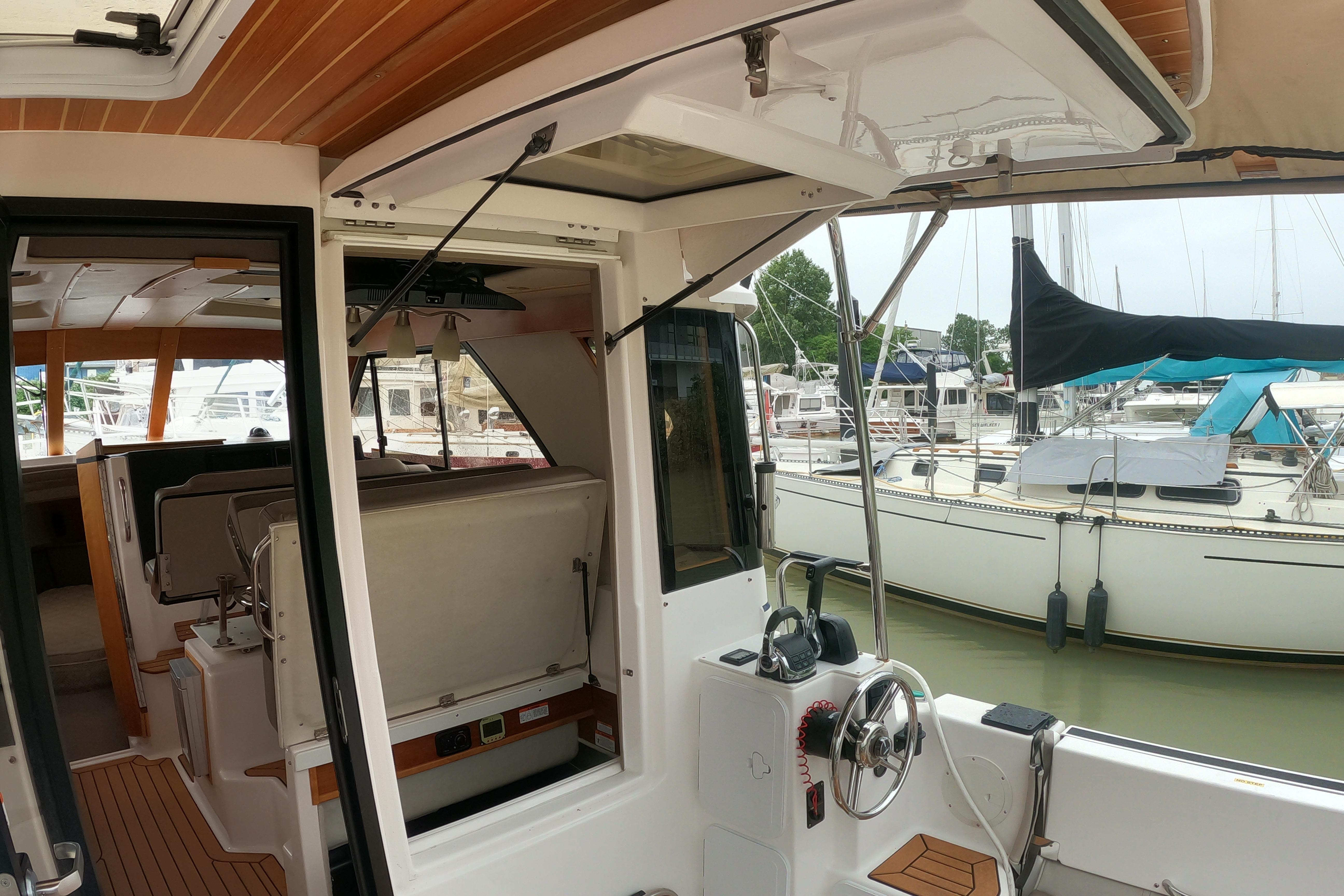 2019 Cutwater C-30 Sedan interior with helm, docked in marina with sailboats.
