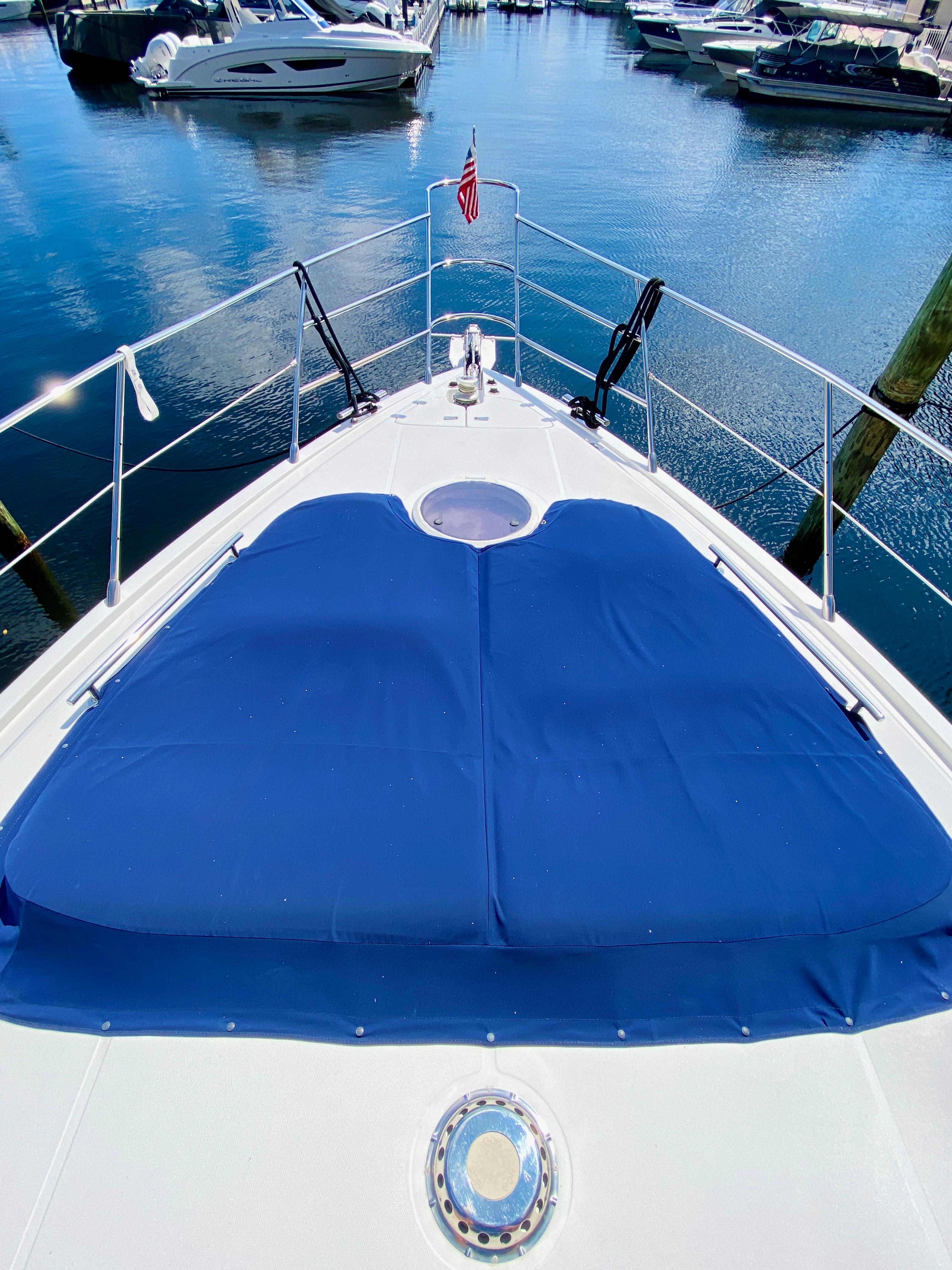 2002 Azimut 55 yacht bow with blue sunpad, docked in marina.