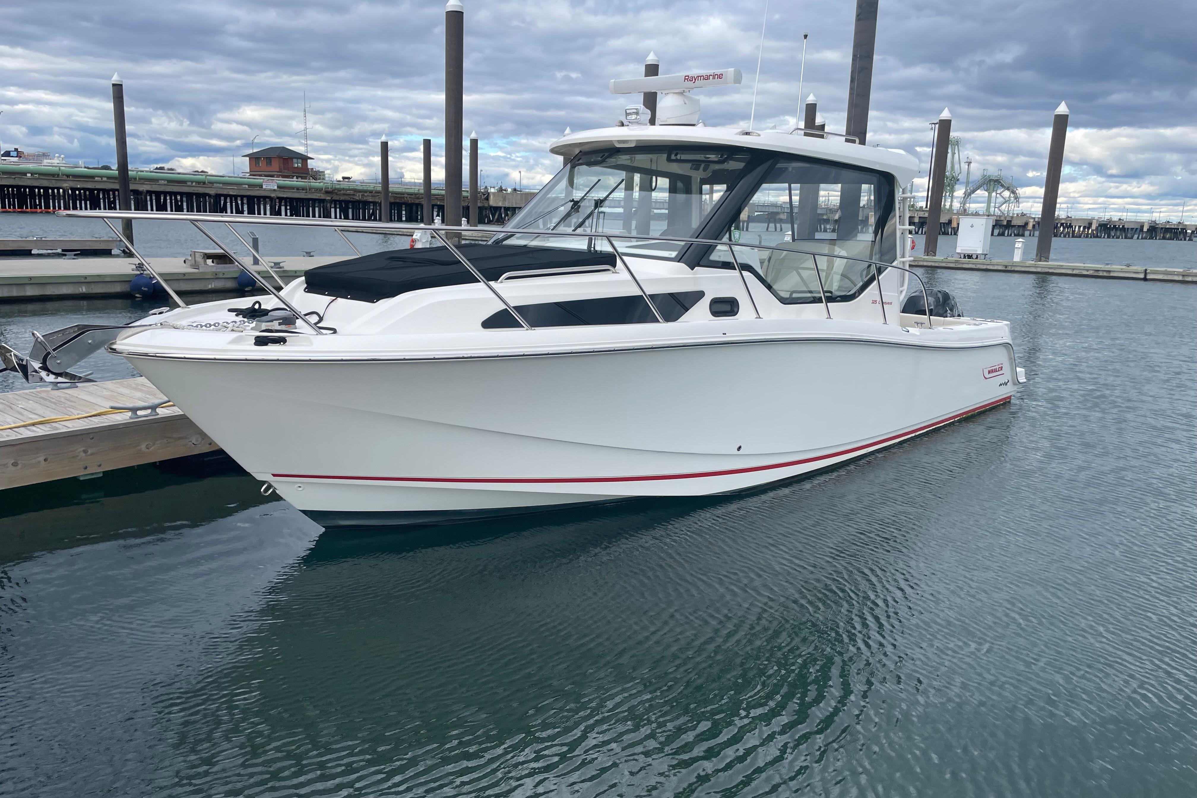 2023 Boston Whaler 325 Conquest boat docked in marina, overcast sky.