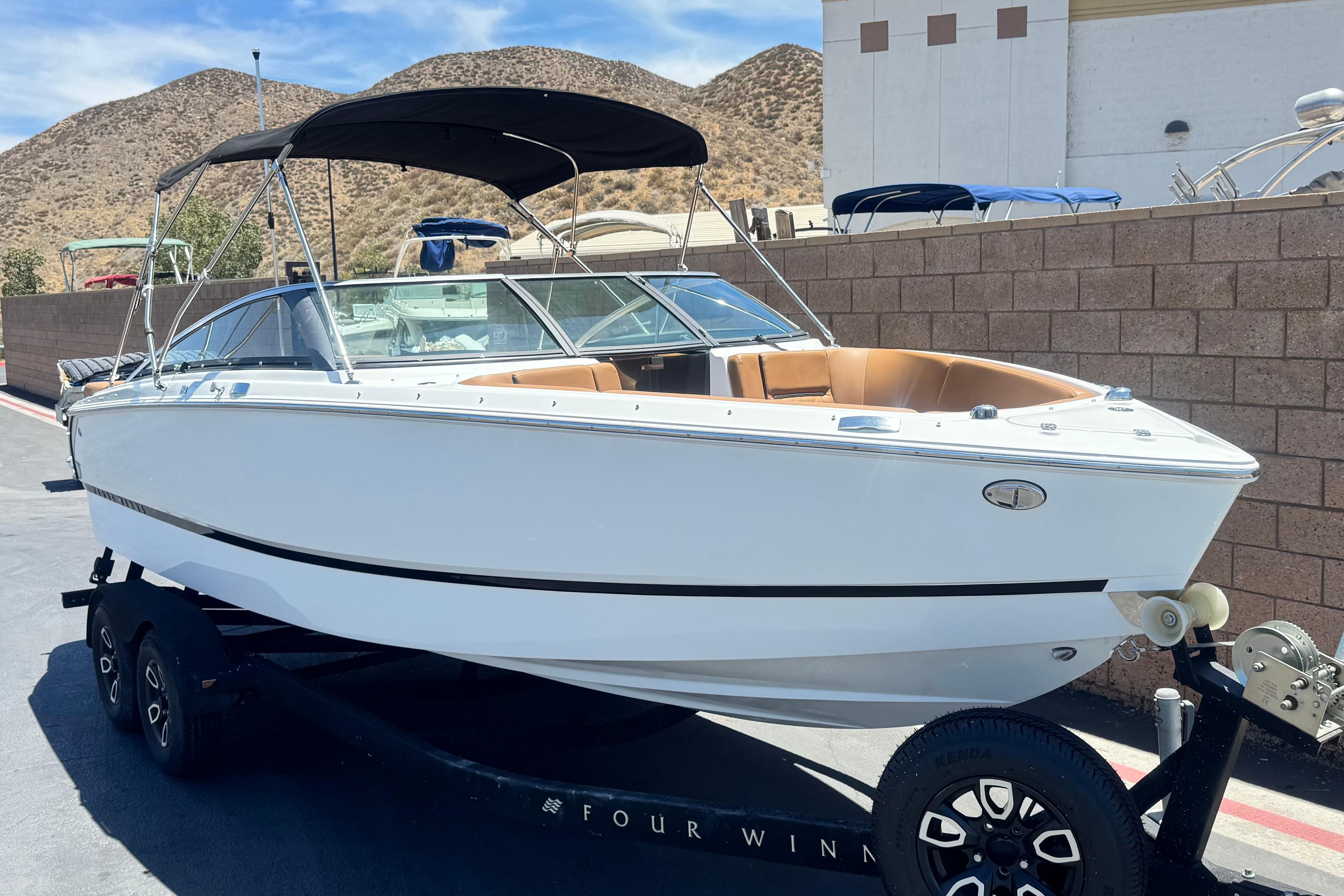 2022 Four Winns H4 boat on trailer, parked outdoors with hills in background.