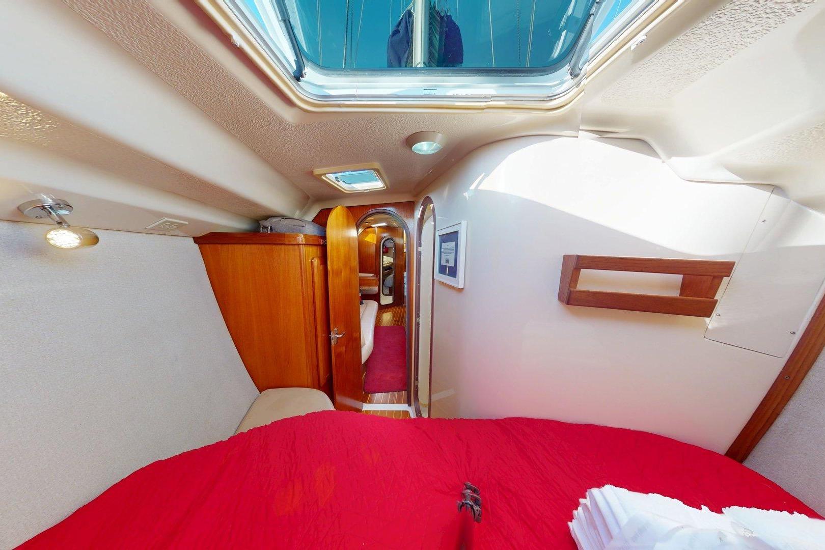 Interior of 1997 Hunter Legend 40.5 sailboat cabin with red bedding and wooden accents.