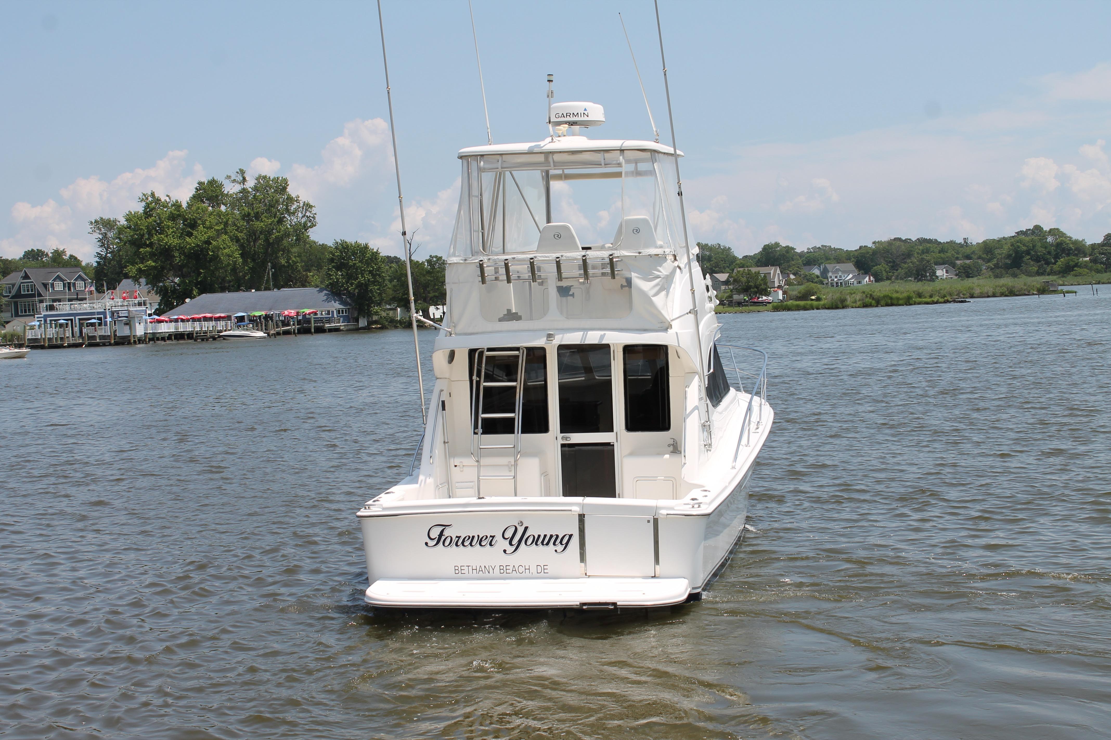 2007 Riviera 33 Flybridge yacht on water, rear view, with scenic background.